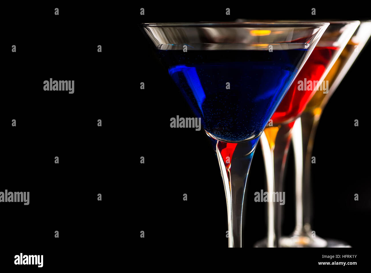 Bunte Cocktails in der Martini-Gläser auf schwarzem Hintergrund. Bar-Werbespots Konzept. Stockfoto