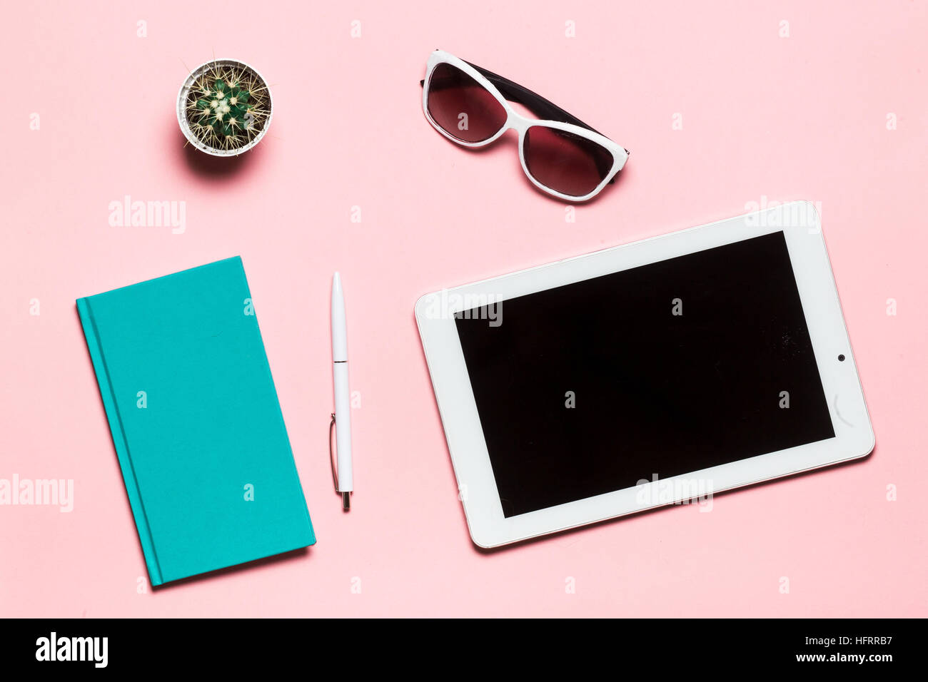 Weiße Tablette, Stift, Brille, Minze-Tagebuch und Kaktus auf rosa Hintergrund. flach legen, Top Aussicht. Stockfoto