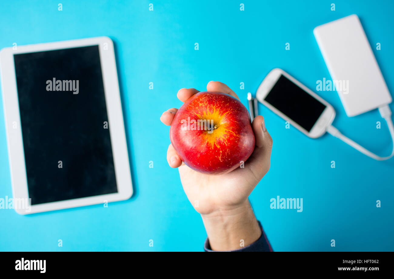 männliche Hand, die einen Apfel am Arbeitsplatz im Büro Stockfoto