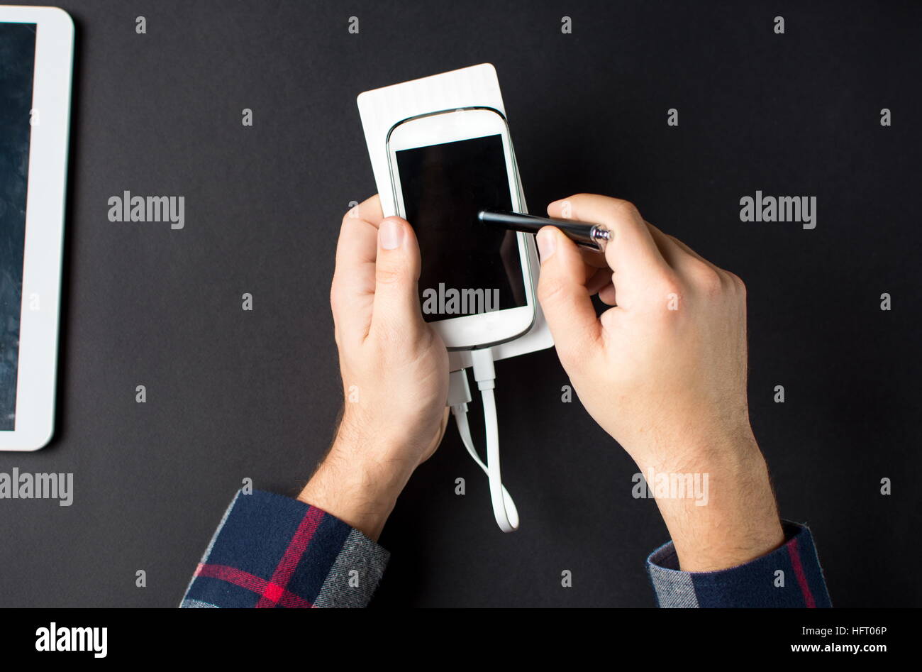 Mann mit einem weißen Handy an ein Ladegerät angeschlossen Stockfoto