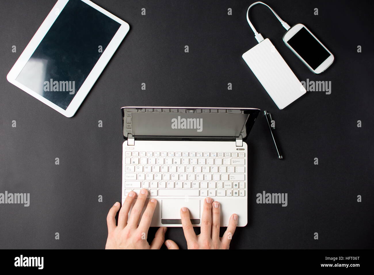 Mann, die Eingabe auf ein weißes Laptop auf schwarzem Hintergrund Stockfoto