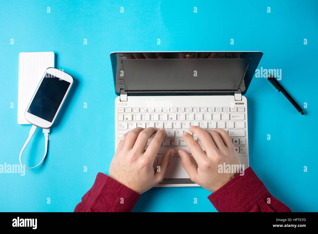 männliche Hände Tippen auf ein weißes Laptop auf blauem Hintergrund Stockfoto