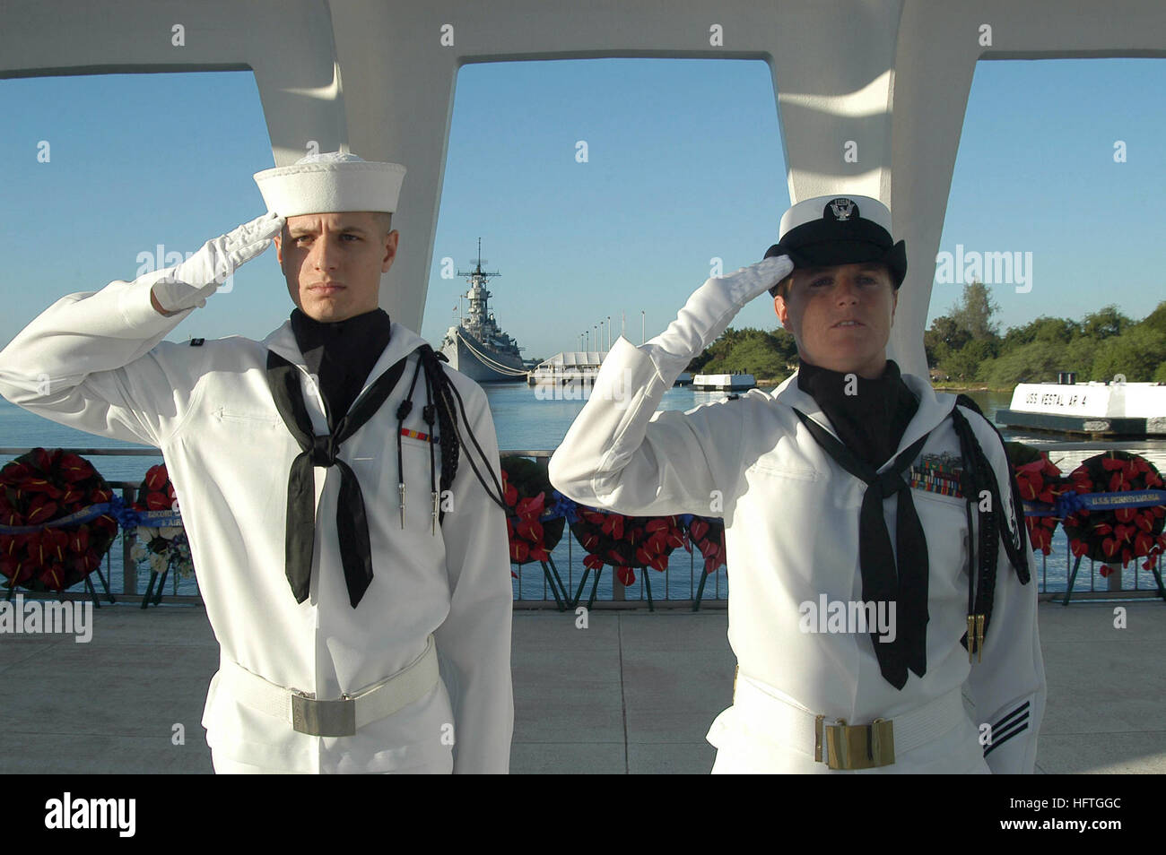 051207-N-6775N-050 Pearl Harbor, Hawaii (7. Dezember 2005) – Maschinen Mechaniker 1. Klasse Michelle Young, rechts, und Seaman Rekrut Joseph Calabro, beide zugewiesen der Navy Region Hawaii zeremonielle Garde, begrüssen die National Fähnrich an Bord der USS Arizona Memorial als die nationale Hymne spielt während der 64. Gedenken an den 7. Dezember 1941 Angriff auf Pearl Harbor, Hawaii. Die Zeremonie, die Bemerkungen von Keynote-Speaker Mullen enthalten, wird jährlich an diejenigen ehren, die während der japanischen Überraschungsangriff auf Pearl Harbor serviert. US Navy Foto vom Fotografen Mate 2. Klasse Justin P. Nesbitt () Stockfoto