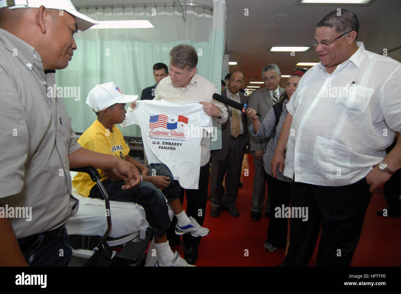 070705-N-0194K-125 COLON, Panama (5. Juli 2007) - Botschafter William Eaton, US-Botschafter in Panama, ein Kind und seinem Vater mit T-shirts als Camilo Alleyne, Minister der Gesundheit für Panama blickt auf eine an Bord des Military Sealift Command Lazarettschiff USNS Comfort (T-AH 20). Komfort ist auf eine viermonatige humanitären Einsatz in Lateinamerika und der Karibik um medizinische Behandlung für Patienten in einem Dutzend Ländern. Während bereitgestellt, ist Komfort unter Betriebskontrolle der US Naval Forces Southern Command und taktische Kontrolle der Zerstörer Geschwader (DESRON) 24. Foto: U.S. Navy Masse Kommunikation Stockfoto