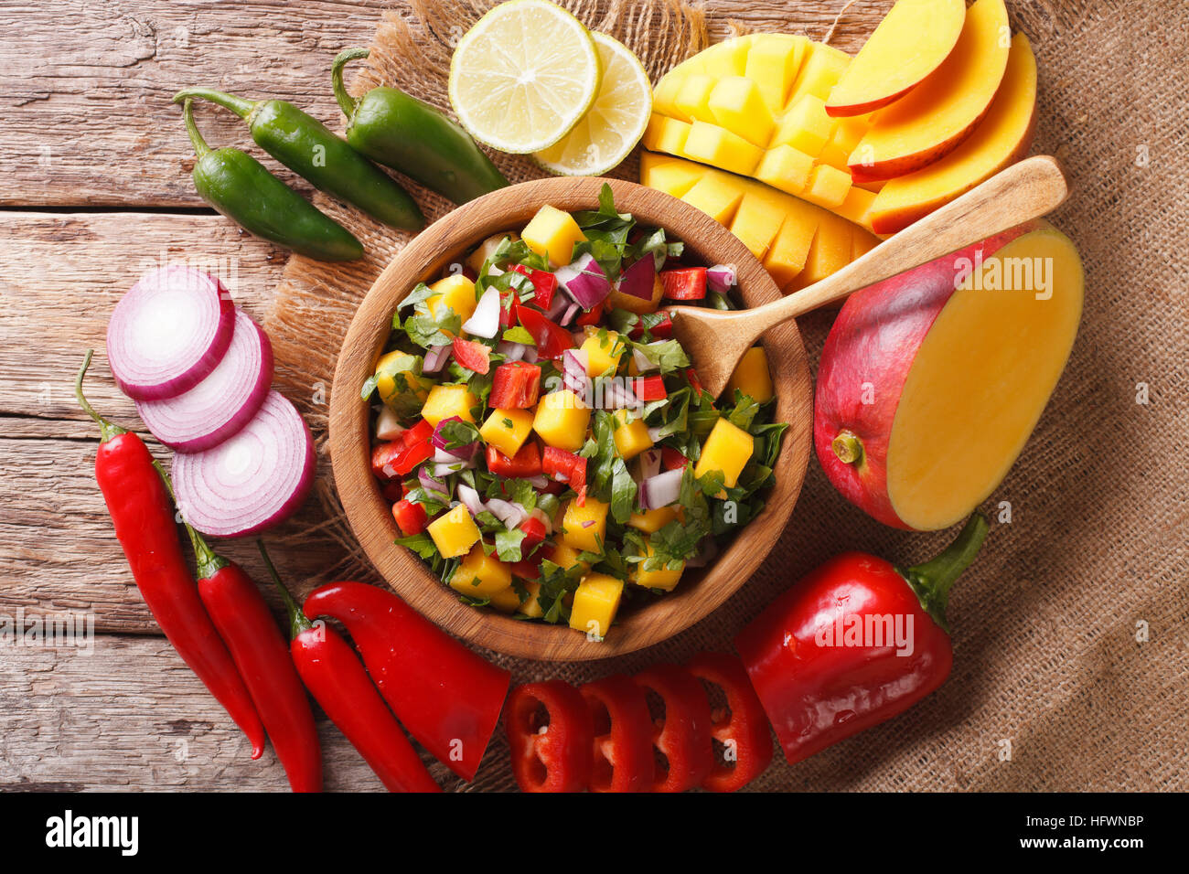 Mexikanisches Essen: Salsa mit Mango, Koriander, Zwiebeln und Paprika hautnah in eine Schüssel geben und die Zutaten auf den Tisch. Horizontale Ansicht von oben Stockfoto