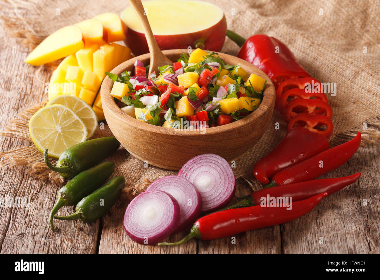Mexikanisches Essen: Salsa mit Mango, Koriander, Zwiebeln und Paprika hautnah in eine Schüssel geben und die Zutaten auf den Tisch. horizontale Stockfoto