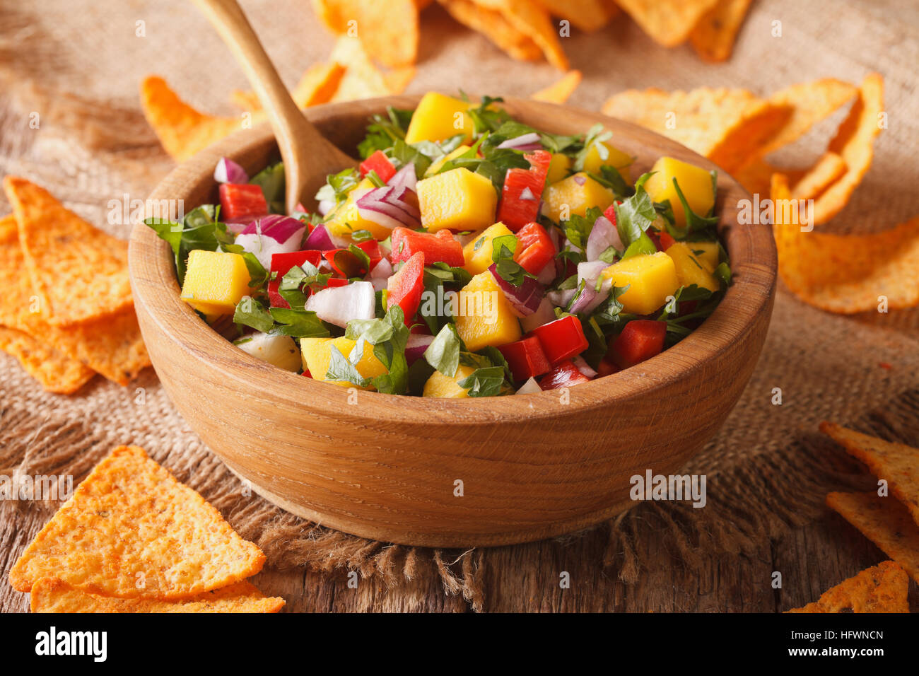 Mexikanische Küche: Salsa mit Mangos, Paprika, Koriander und Zwiebeln in einer Schüssel und Mais-Chips auf dem Tisch hautnah. horizontale Stockfoto