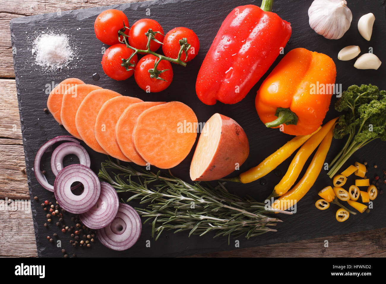 Pflanzliche Inhaltsstoffe: Süßkartoffeln, Paprika, Tomaten, Zwiebeln,  Knoblauch, Rosmarin und Gewürze Nahaufnahme auf einer Schiefertafel Tafel.  horizontale Ansicht von oben Stockfotografie - Alamy