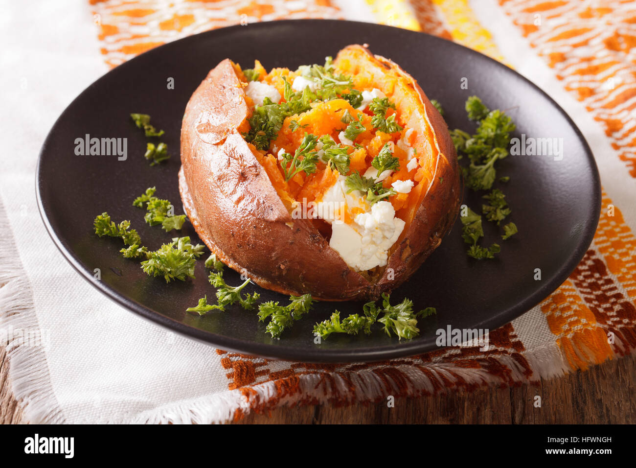 tolles Essen: süße Kartoffeln gebacken mit Frischkäse, Butter und Petersilie Nahaufnahme auf einer schwarzen Platte auf den Tisch. horizontale Stockfoto