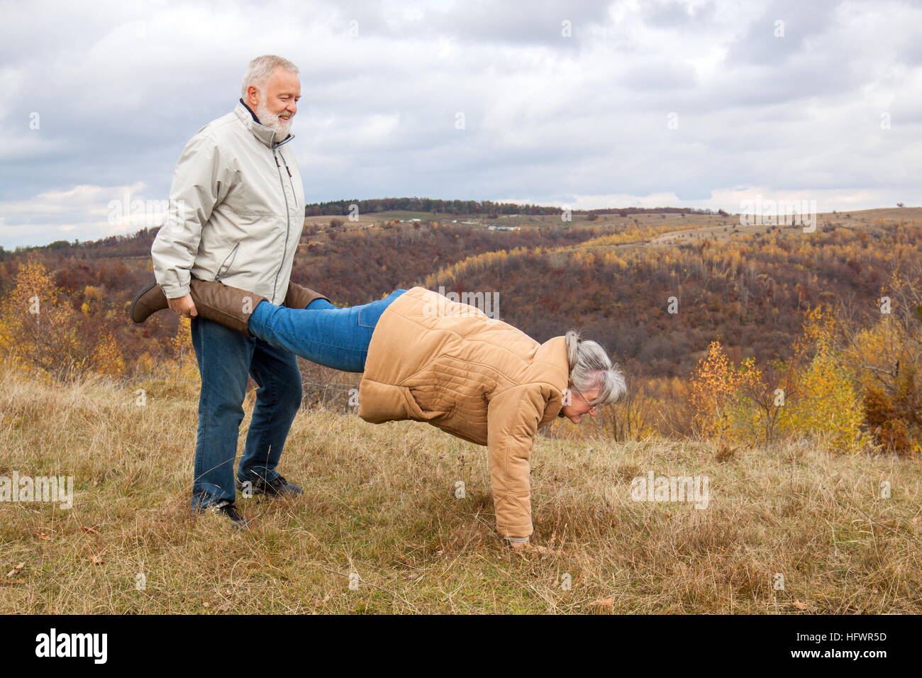 Ältere Paare Spaß und spielen die Schubkarre in der Natur. Stockfoto