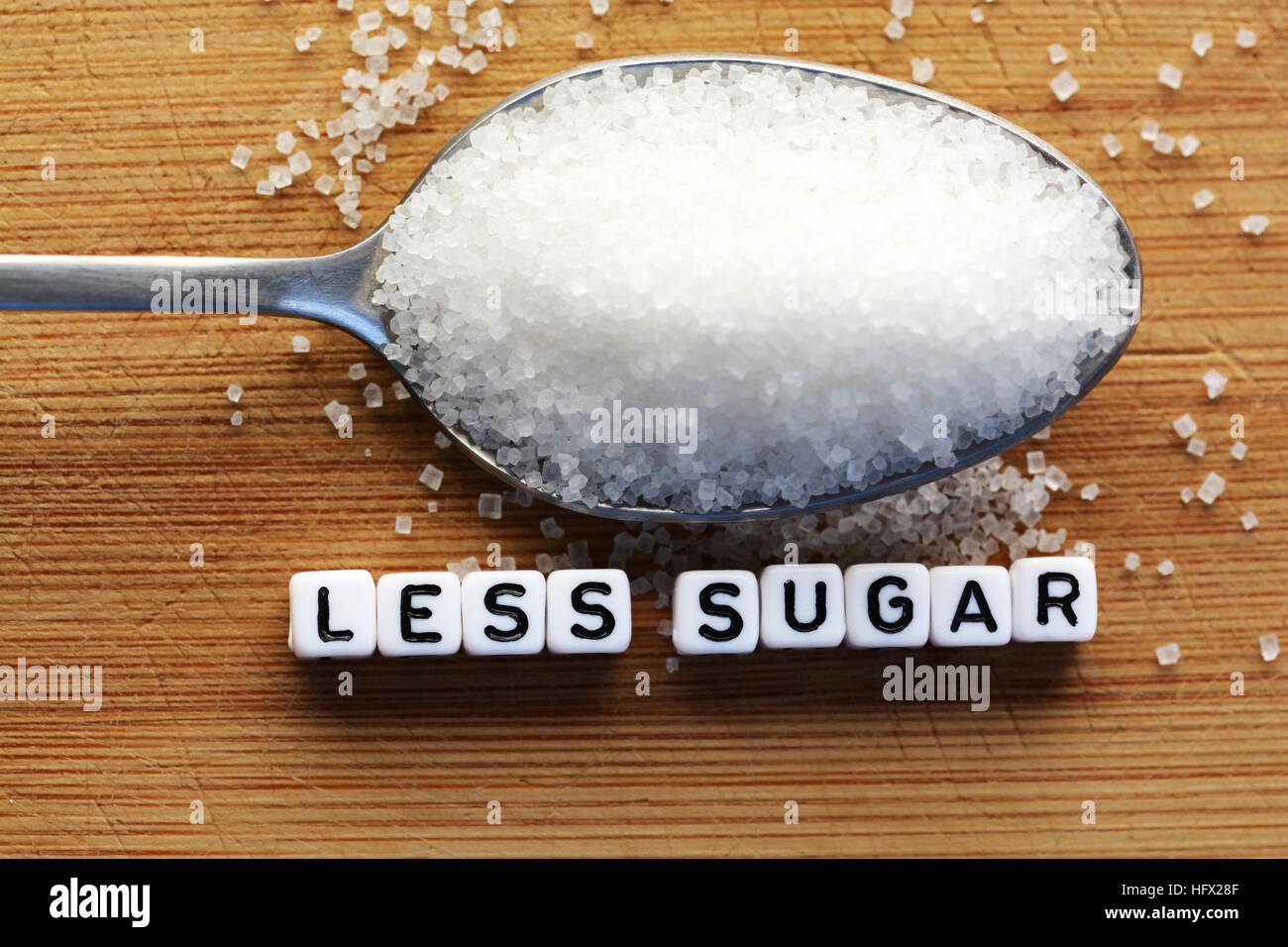 Weniger Zucker Text von gefliesten Buchstaben-Blöcke und Zucker Haufen auf einem Löffel, was darauf hindeutet, Diät Konzept Stockfoto