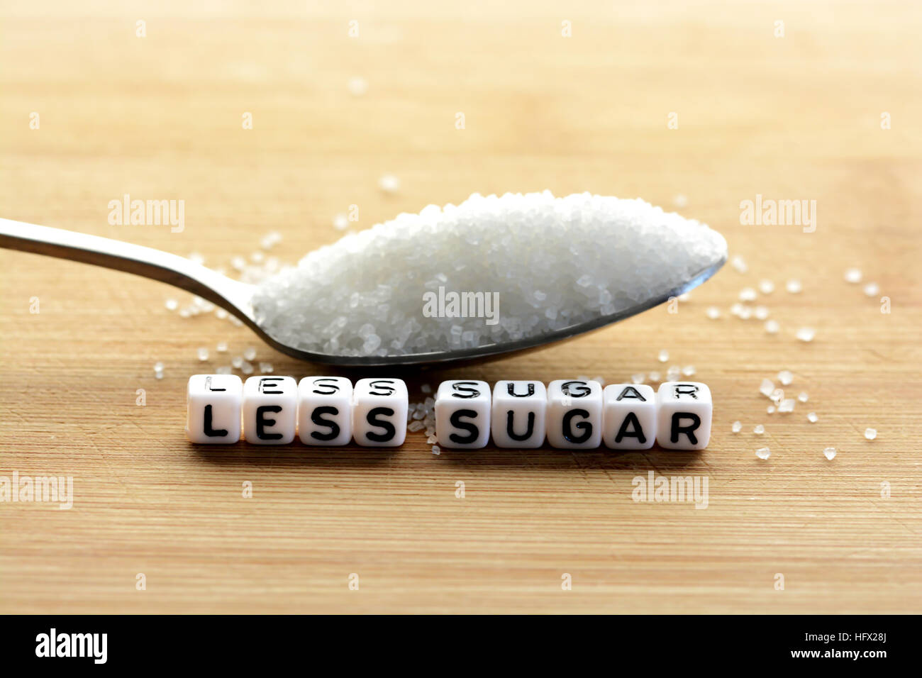 Weniger Zucker Text von gefliesten Buchstaben-Blöcke und Zucker Haufen auf einem Löffel, was darauf hindeutet, Diät Konzept Stockfoto
