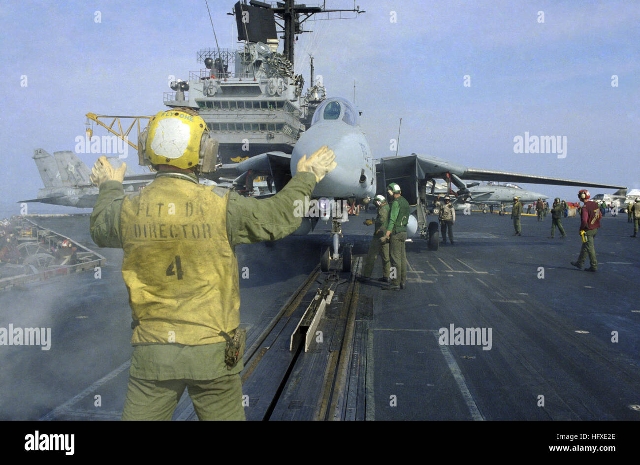 Eine F-14 Tomcat wird von einem Flugzeugdirektor in Position auf dem Katapult der USS Saratoga (CV-60) geführt. Die Flugzeugträger bieten Lufteinsätze, Projektionen und unterstützen Marinemissionen. Stockfoto