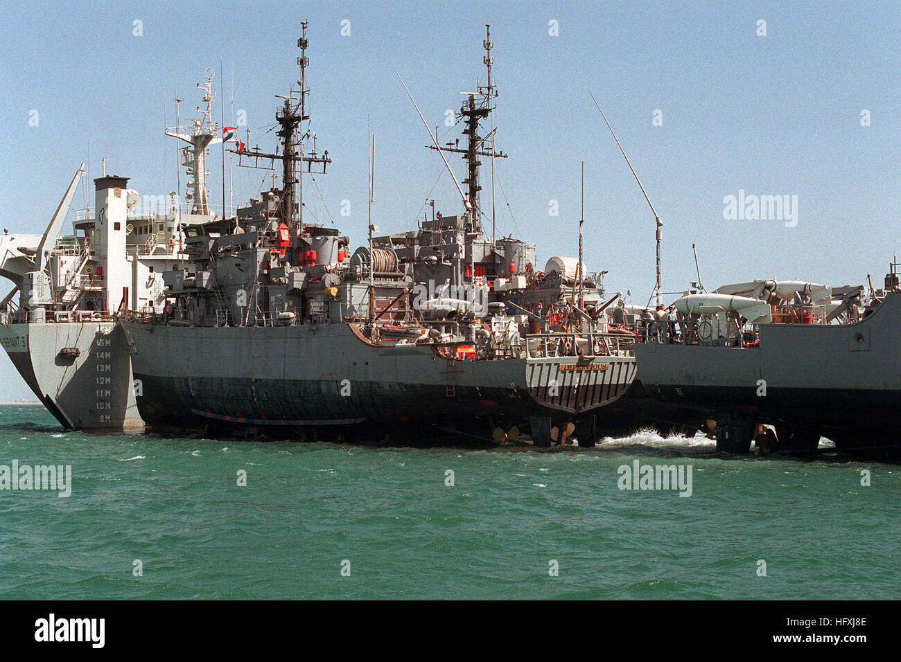 Die Minensuchmaschine USS Impeficious und weitere Schiffe befinden sich auf dem teilweise untergetauchten Deck des niederländischen Schwerlastschiffs Super Servant 3, bevor sie zur Unterstützung der Operation Desert Shield entladen werden. Stockfoto