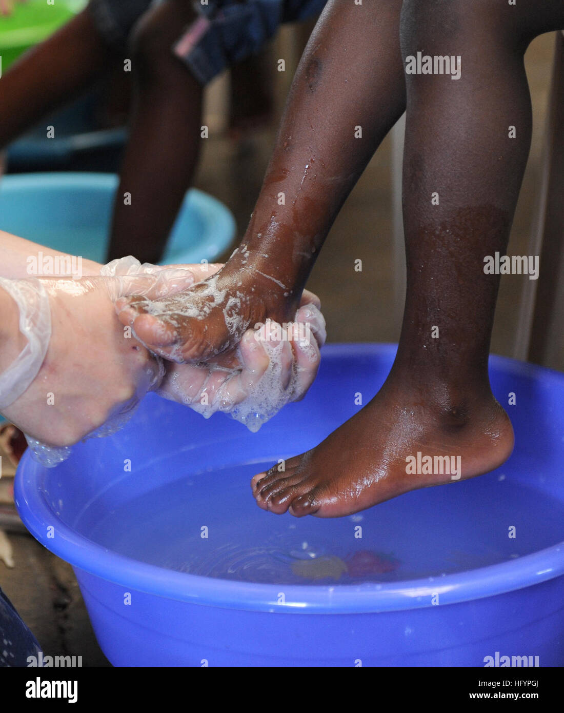 110421-F-ET173-062 KINGSTON, Jamaika (21. April 2011) A Sailor wäscht ein Kind Füße bevor Sie ihm ein paar neue Schuhe während einer anhaltenden Versprechen geben Schuh Werbegeschenk. Die Veranstaltung wurde gesponsert von Samaritan es Füße, eine nichtstaatliche Organisation, spezialisiert auf Schuhe für Menschen, die nicht leisten können. Weiterhin verspricht eine fünfmonatige humanitäre Hilfsmission, Karibik, Mittel- und Südamerika.  (US Air Force Foto von Staff Sgt. Alesia D. Goosic/freigegeben) US Navy 110421-F-ET173-062 A Sailor wäscht die Füße des Kindes bevor Sie ihm ein paar neue Schuhe während einer anhaltenden P geben Stockfoto
