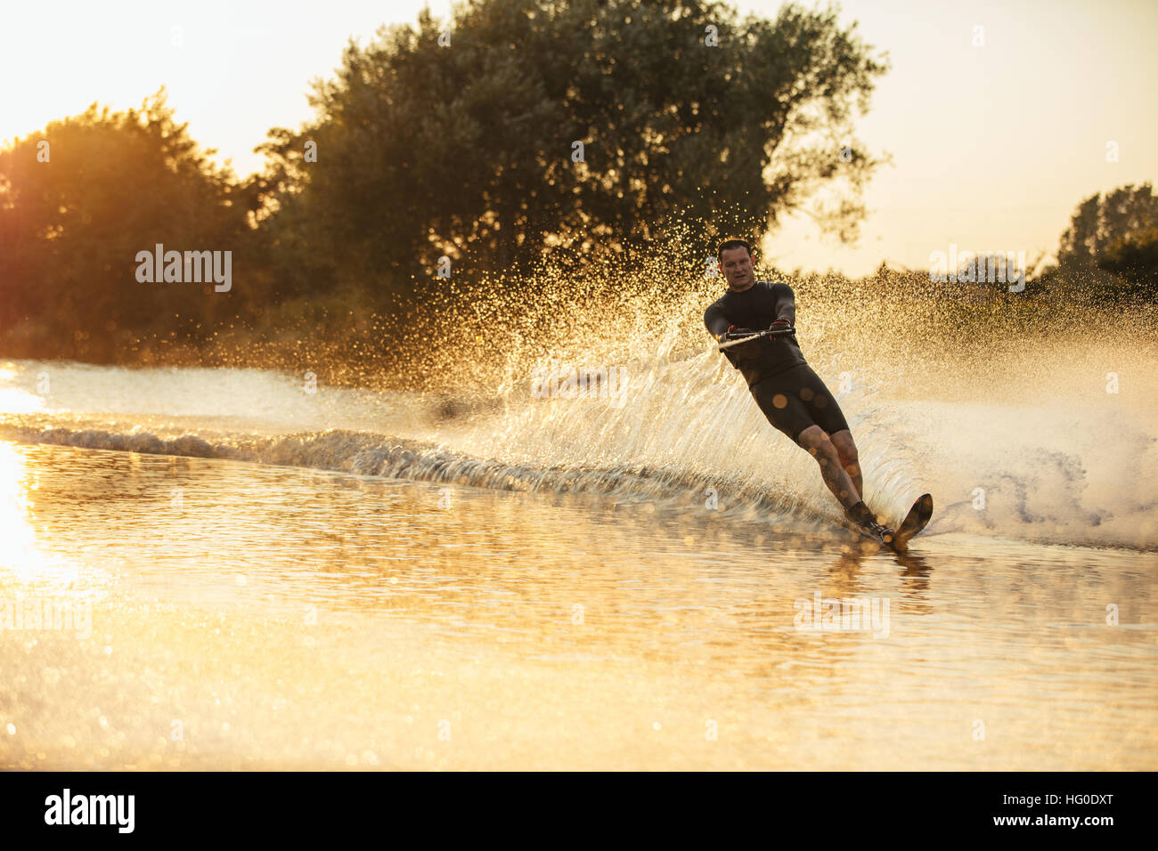 Mann Wakeboarden an einem See mit Spritzer Wasser. Wakeboarder Surfen über den See. Stockfoto