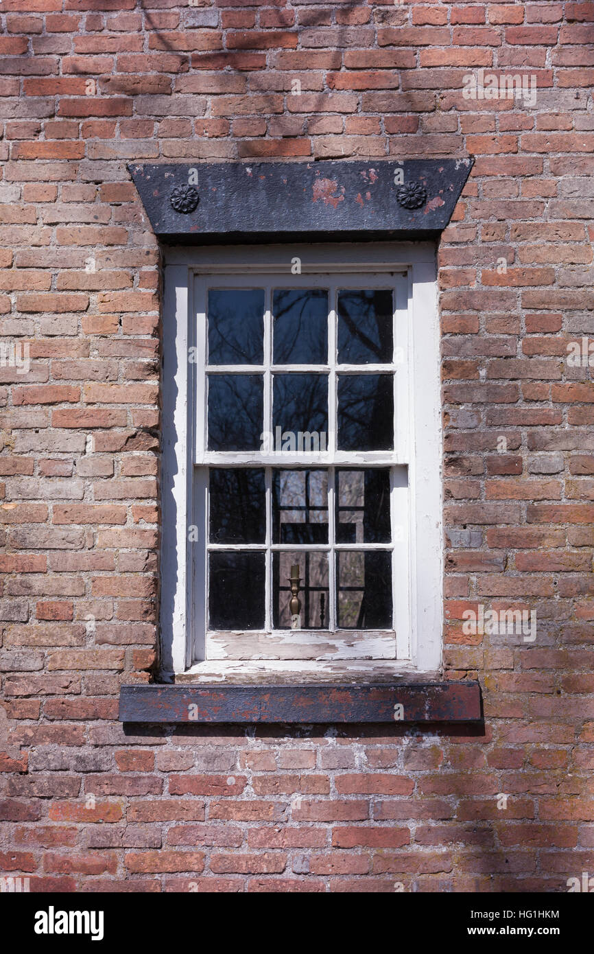 Ein altes Fenster mit Glasscheiben auf ein Ziegelhaus. Stockfoto