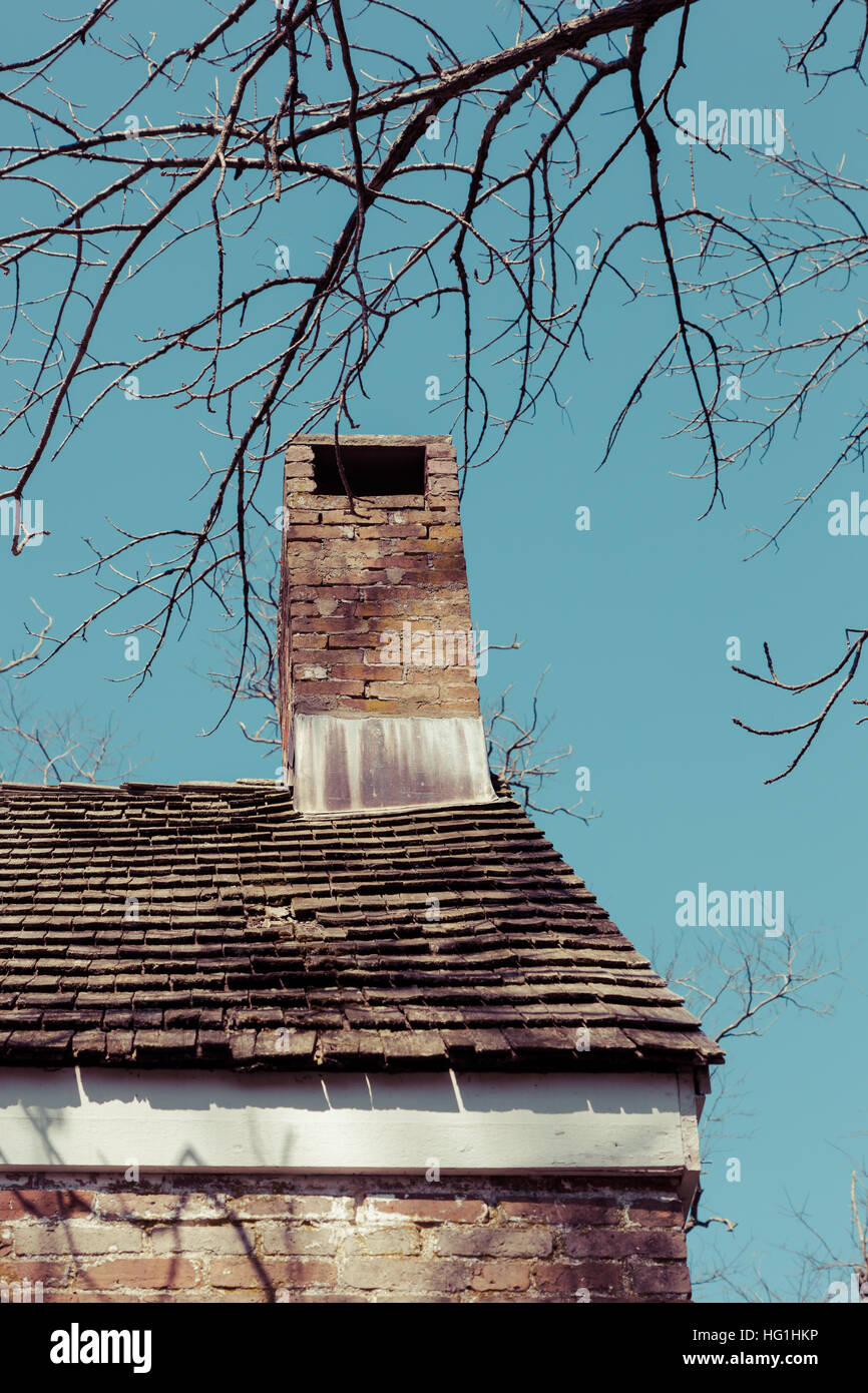 Details eines alten Schornstein und verwitterte Dach mit Zederschindeln auf einem alten Backsteinhaus. Stockfoto