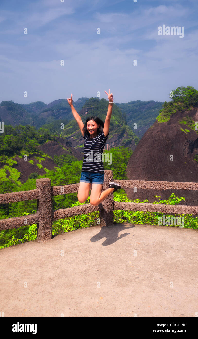 Eine Chinesin springen vor Freude auf einer Plattform innerhalb der Wuyishan landschaftlich reizvollen Gegend in der Provinz Fujian China. Stockfoto