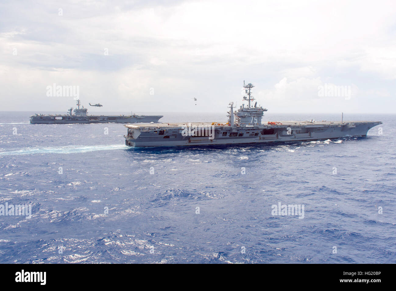 US-Marine MH-60 Seahawk Hubschrauber Transport Fracht zwischen den Flugzeugträger USS Harry S. Truman (CVN-75), Vordergrund und der USS Theodore Roosevelt (CVN-71) im Atlantischen Ozean 16. Juli 2014. Der Truman und Theodore Roosevelt wurden im Gange einen Munition Transfer durchführen. (Foto: U.S. Navy Mass Communication Specialist 3. Klasse Karl Anderson/freigegeben) USS Harry S. Truman Operationen 140716-N-ZG705-0967 Stockfoto
