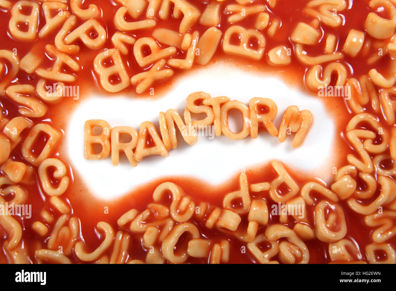 Das Wort "Brainstorming" geschrieben in Alphabetti Spaghetti, orangefarbene Nudeln Buchstaben geformt. Stockfoto