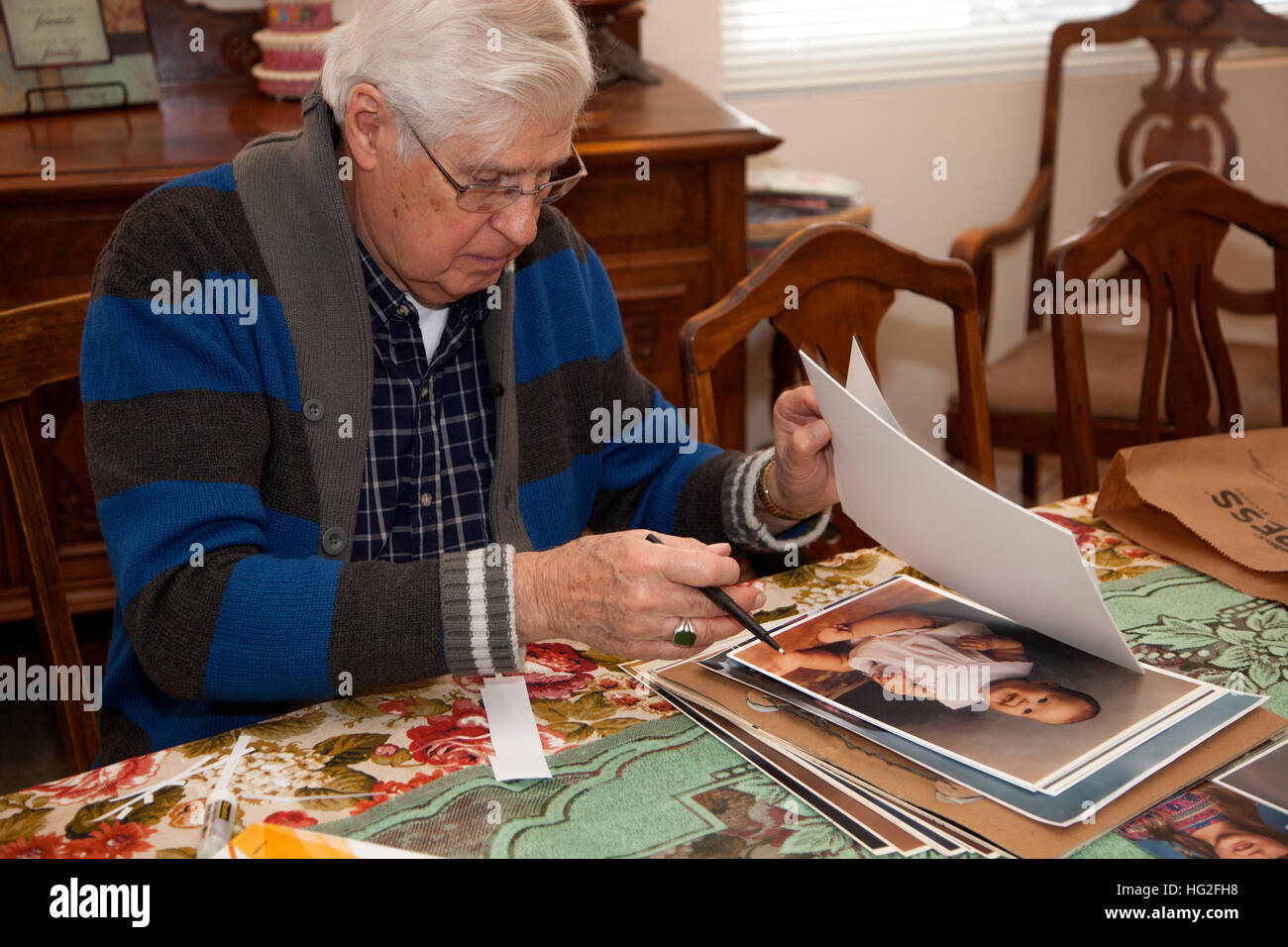 Älteren Erwachsenen Mannes Auswahl von Fotos für ein Familienalbum. Downers Grove Illinois IL USA Stockfoto