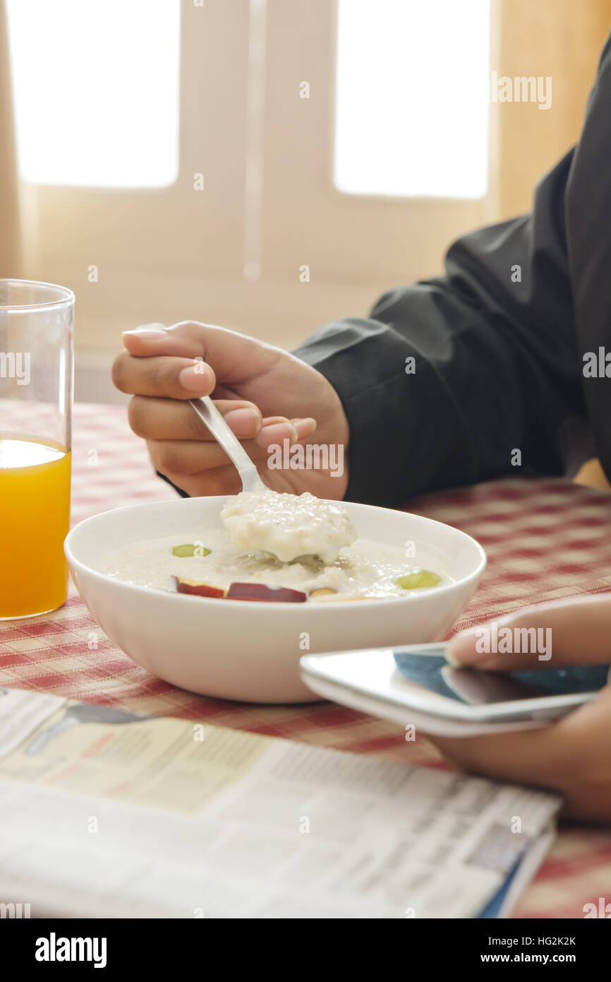 Mann mit Handy beim Frühstück Stockfoto