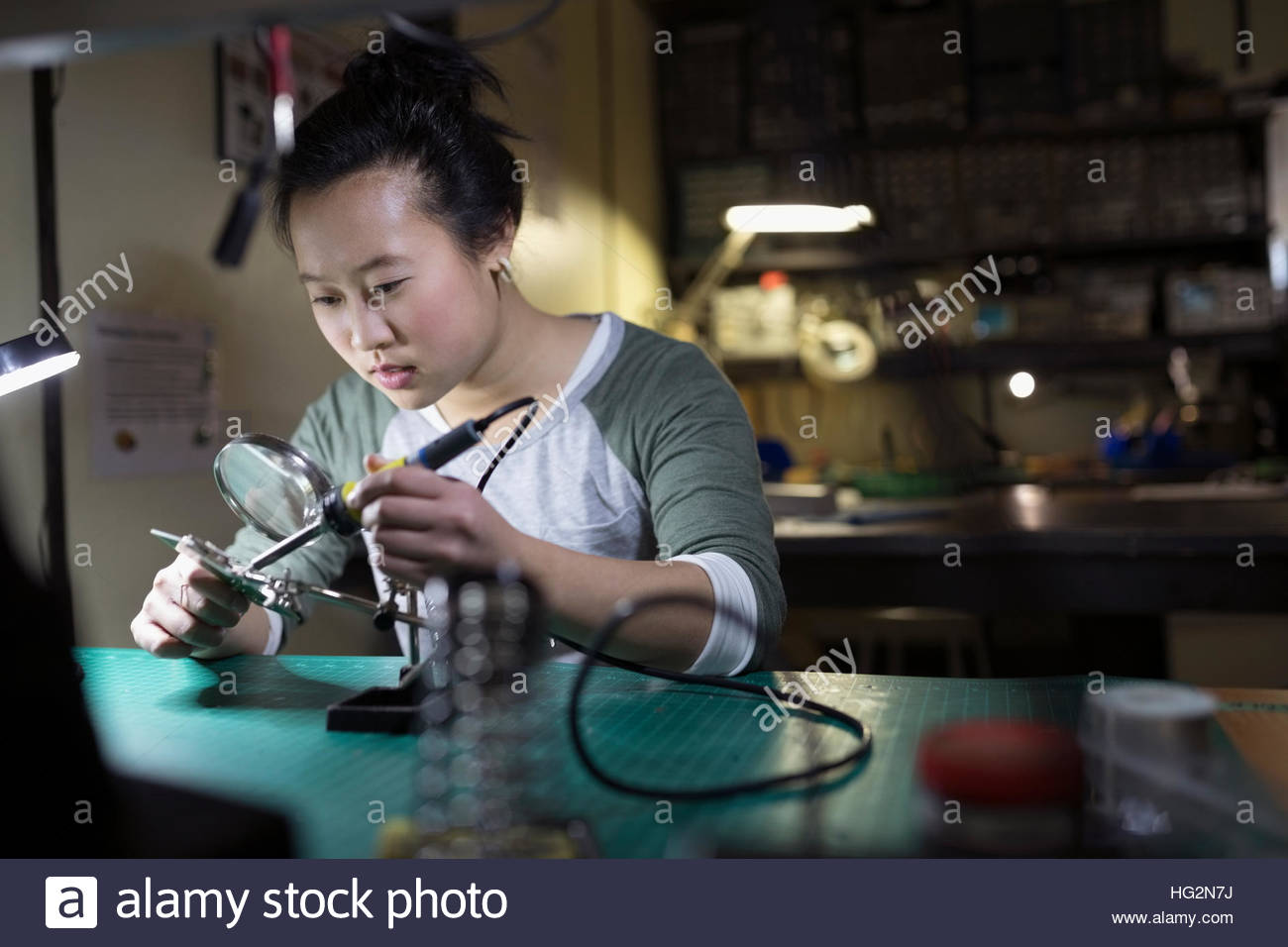 Weibliche Elektroniker mit Lötkolben an Werkbank in Werkstatt Stockfoto