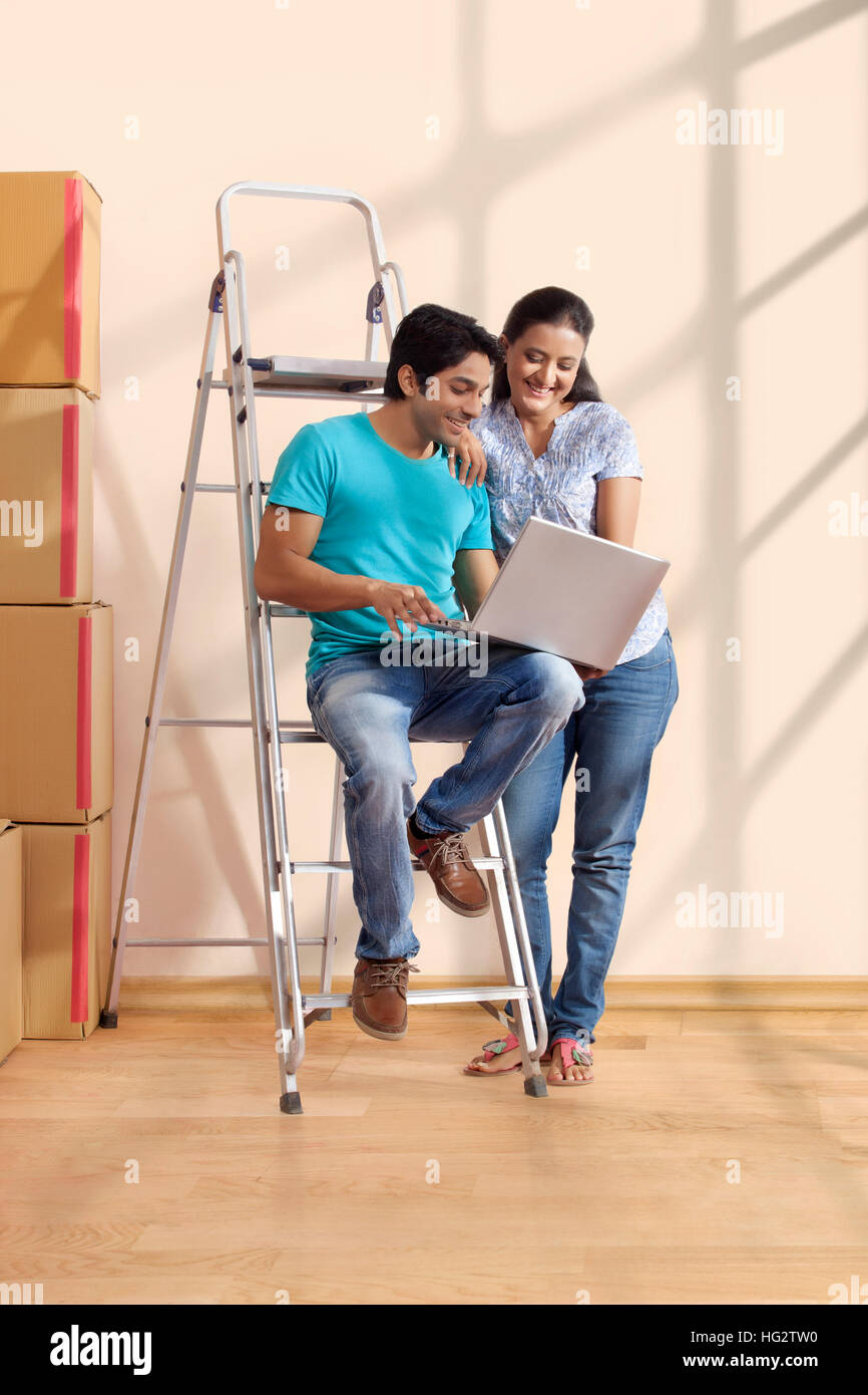 Porträt eines jungen Paares mit einem Laptop stehen auf der Leiter Stockfoto