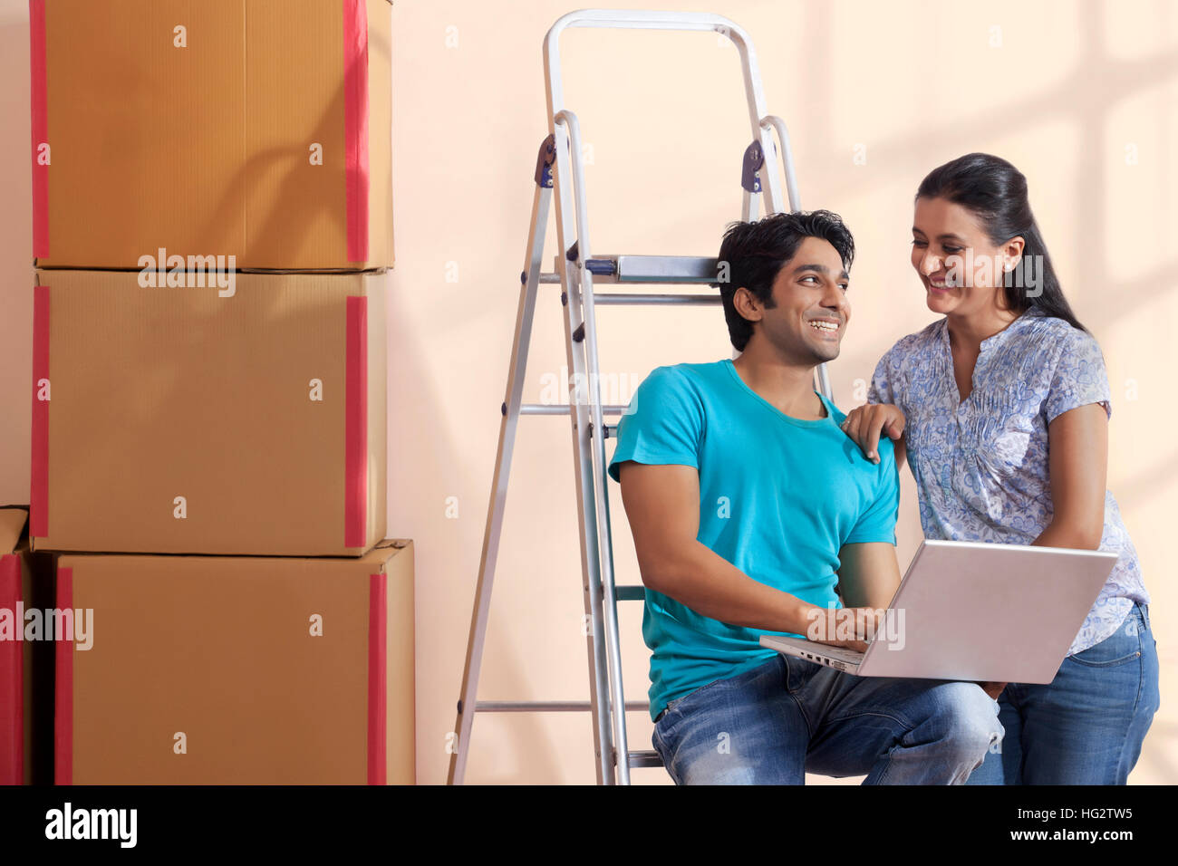 Porträt eines jungen Paares mit einem Laptop stehen auf der Leiter Stockfoto