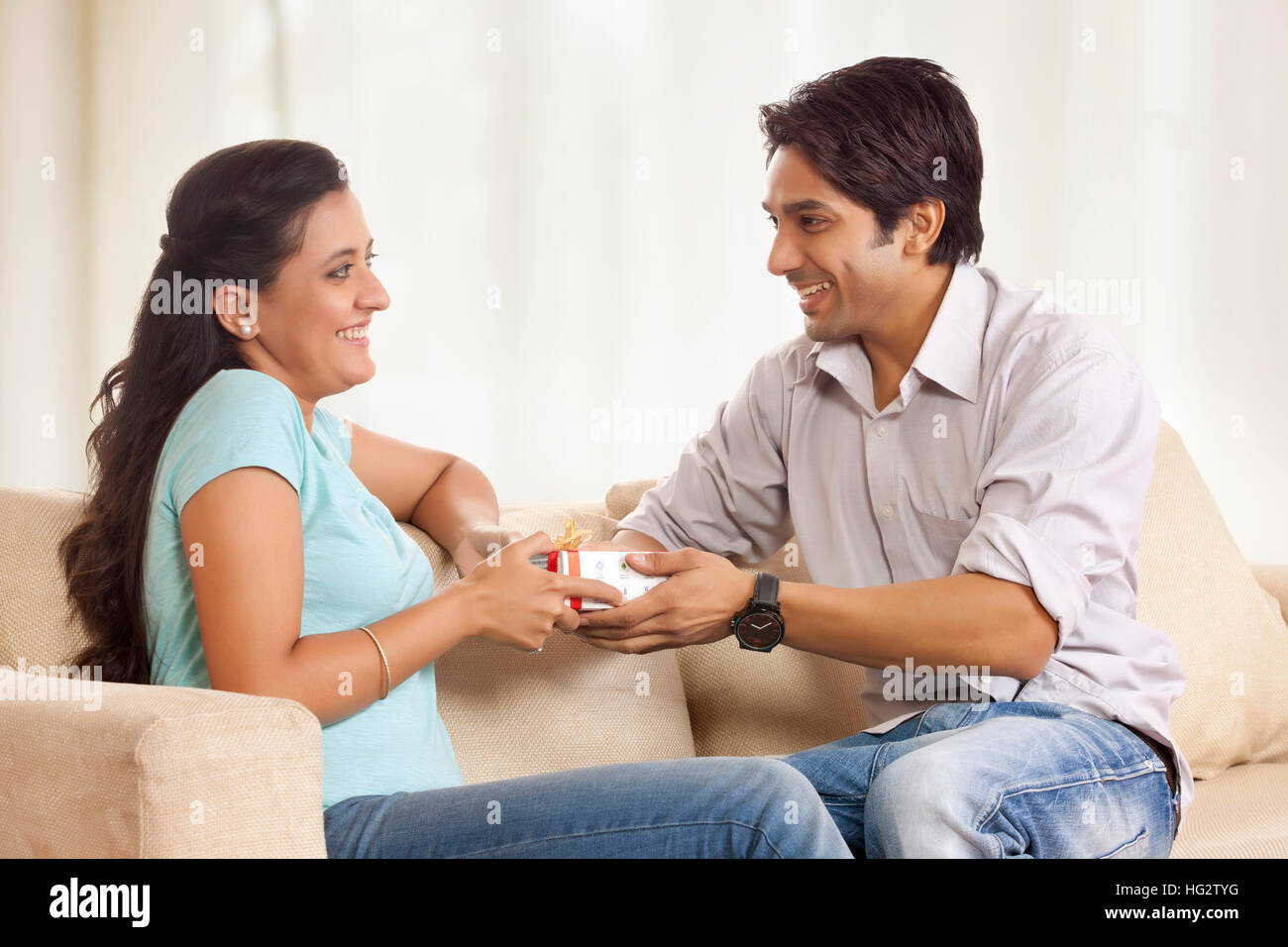 Mann die Freundin Geschenk auf sofa Stockfoto