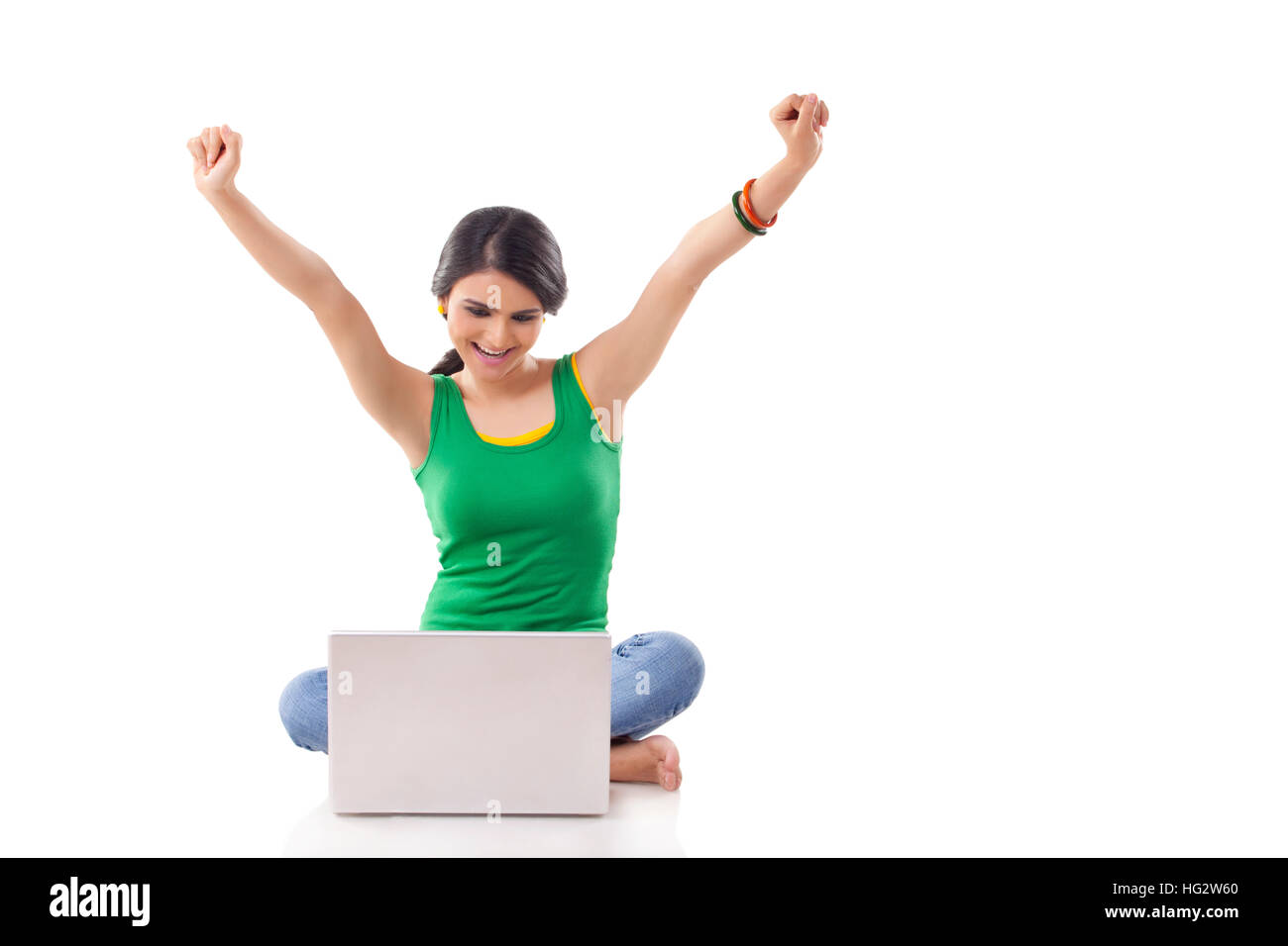 Junge Frau Jubel bei Kamera mit Laptop auf dem Boden Stockfoto