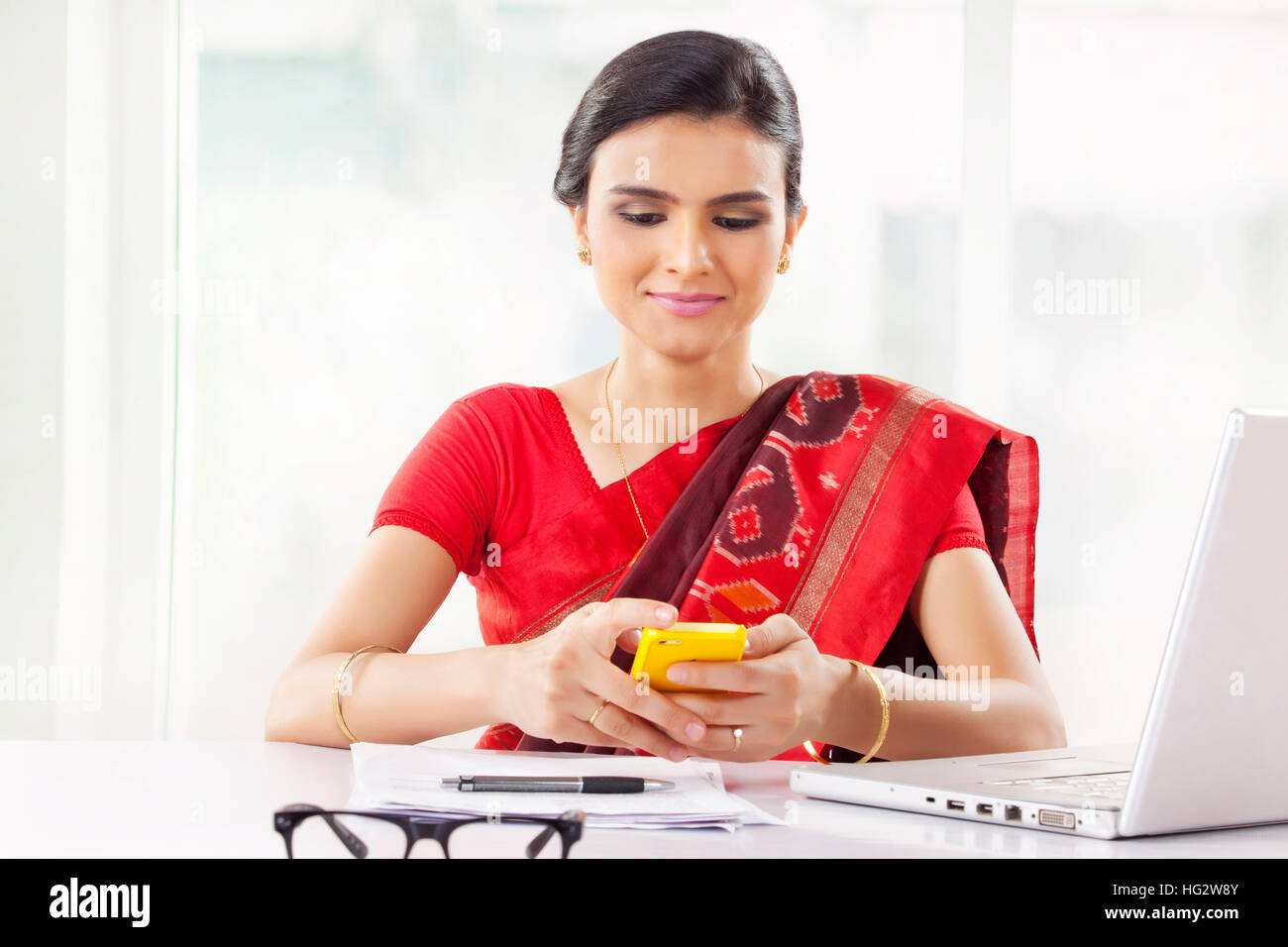 Indische Frau, die im Büro mit Handy Stockfoto