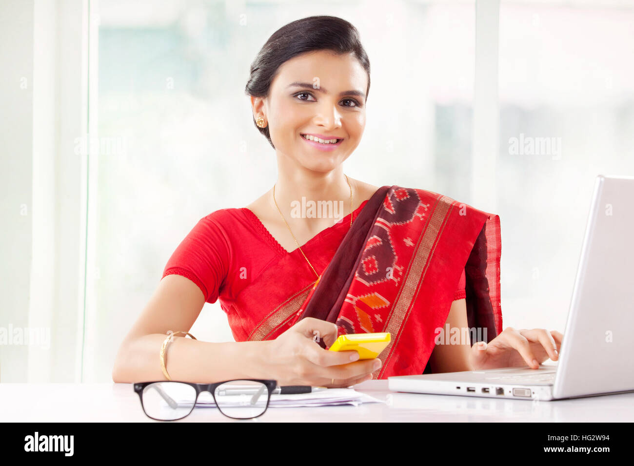 Indische Frau, die im Büro mit Handy Stockfoto