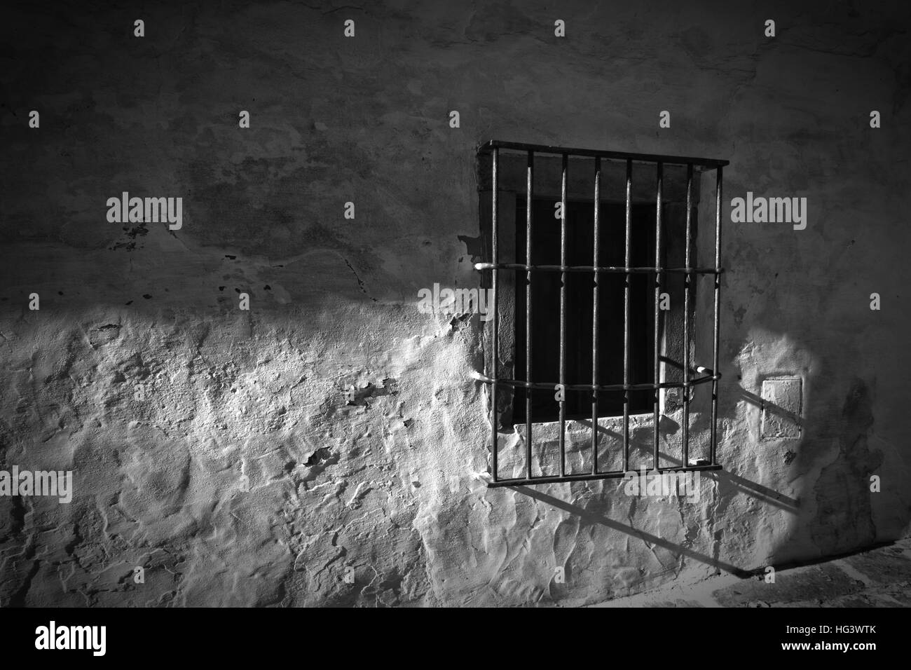 BW-Foto des Fensters mit Eisenstangen an weißer Wand und Kopfsteinpflaster Weg Stockfoto BW-Foto des Fensters mit Eisenstangen an weißer Wand und Kopfsteinpflaster Weg Stockfoto