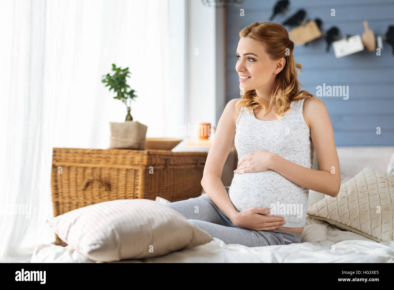 Schwangere Frau sitzt in einem Schlafzimmer Stockfoto