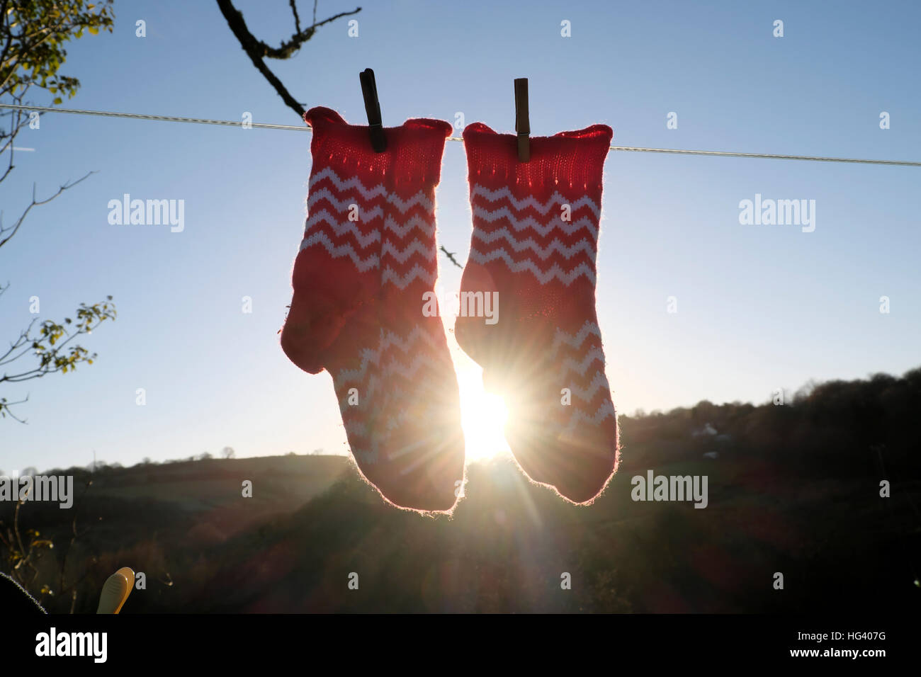 Rote und weiße Zick-Zack-Muster auf wolligen Socken hängen, Wäscheleine im Winter bei Sonnenschein flare ländlichen Wales UK KATHY DEWITT Stockfoto