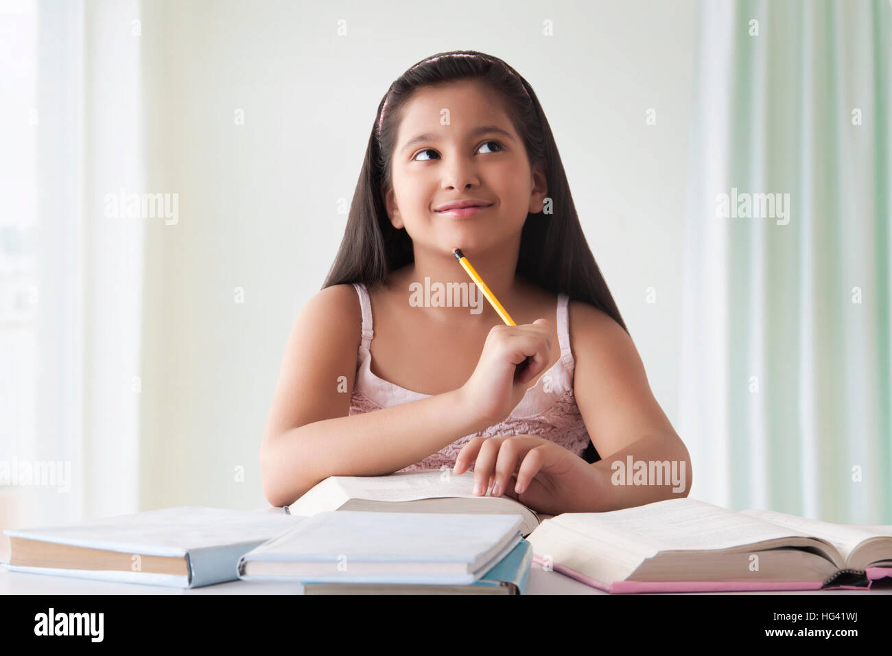 Porträt der lächelnde niedliche Mädchen denken am Schreibtisch mit Bücher Stockfoto