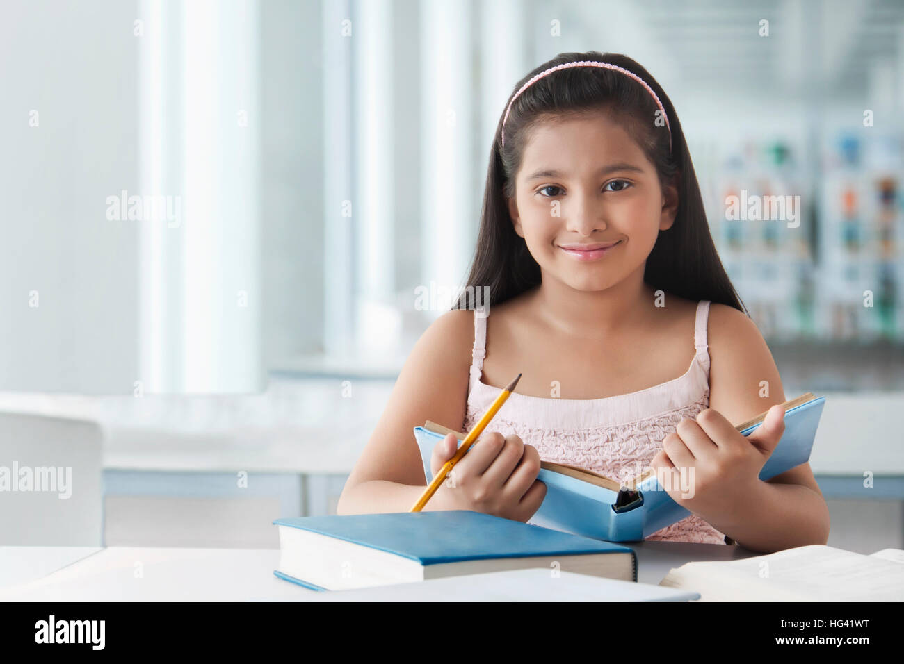Portrait von lächelnden cute girl am Schreibtisch mit Bücher Stockfoto