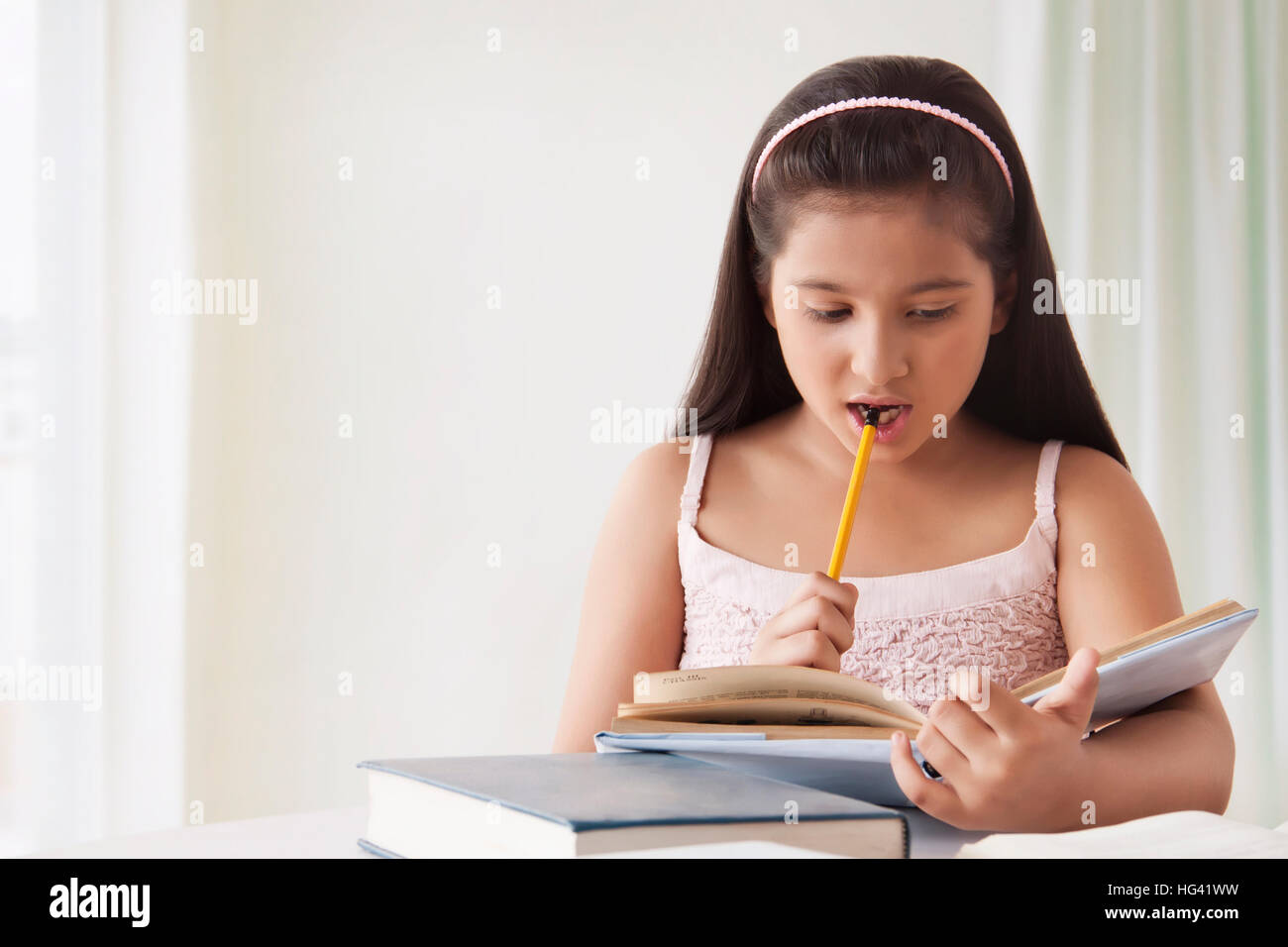 Portrait von cute girl Kaut ihr Bleistift während des Studiums Stockfoto