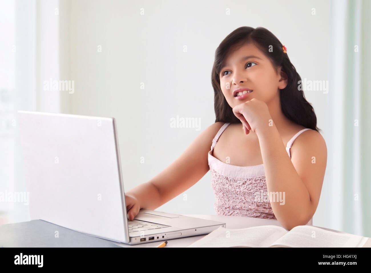 Portrait von süße Mädchen denken, während mit Laptop Stockfoto