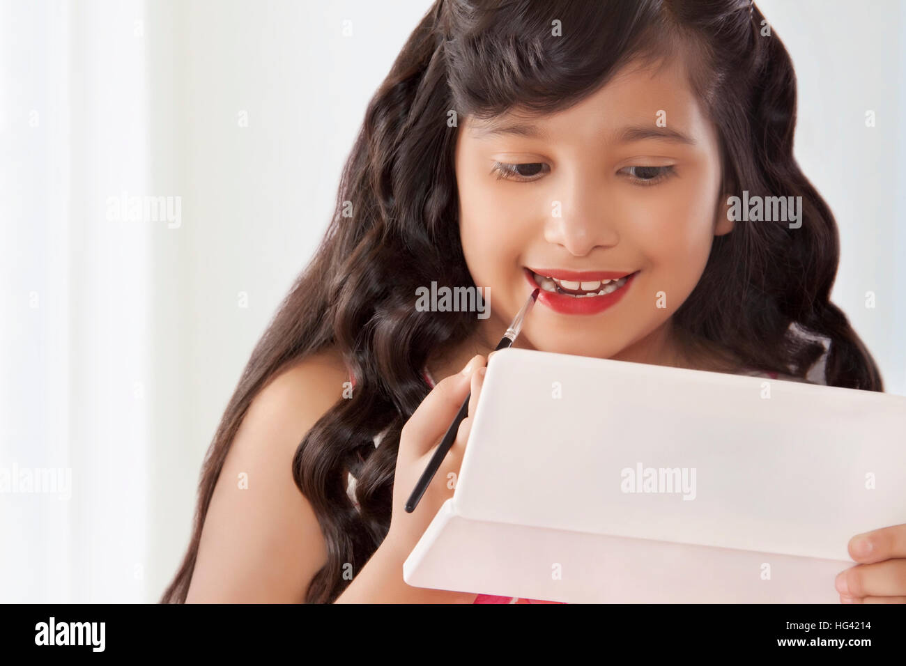 Süße Mädchen setzen auf Lippenstift in Spiegel Stockfoto