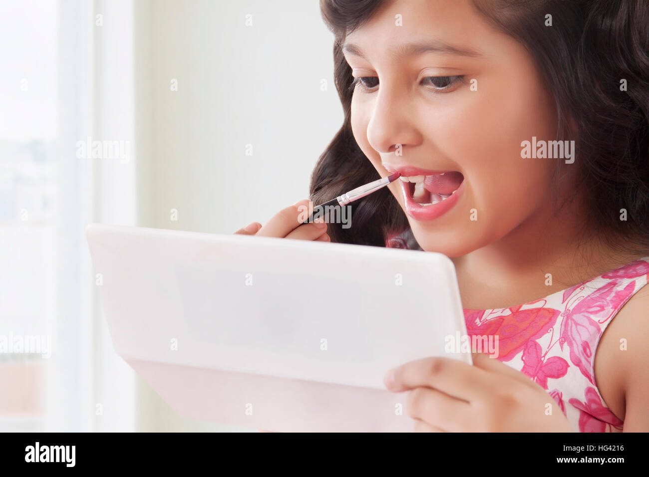 Süße Mädchen setzen auf Lippenstift in Spiegel Stockfoto