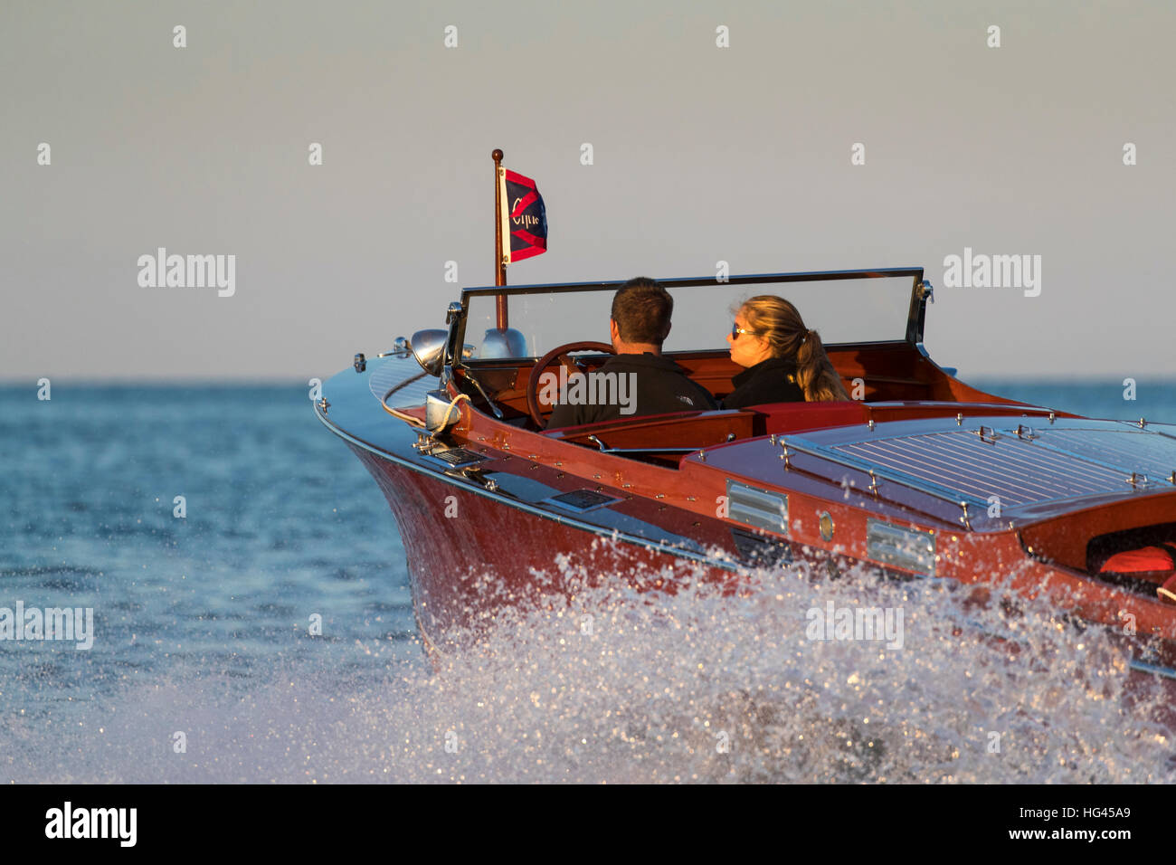 Ein junges Paar, eine antiken, hölzerne Chris-Craft Boot fahren. Stockfoto