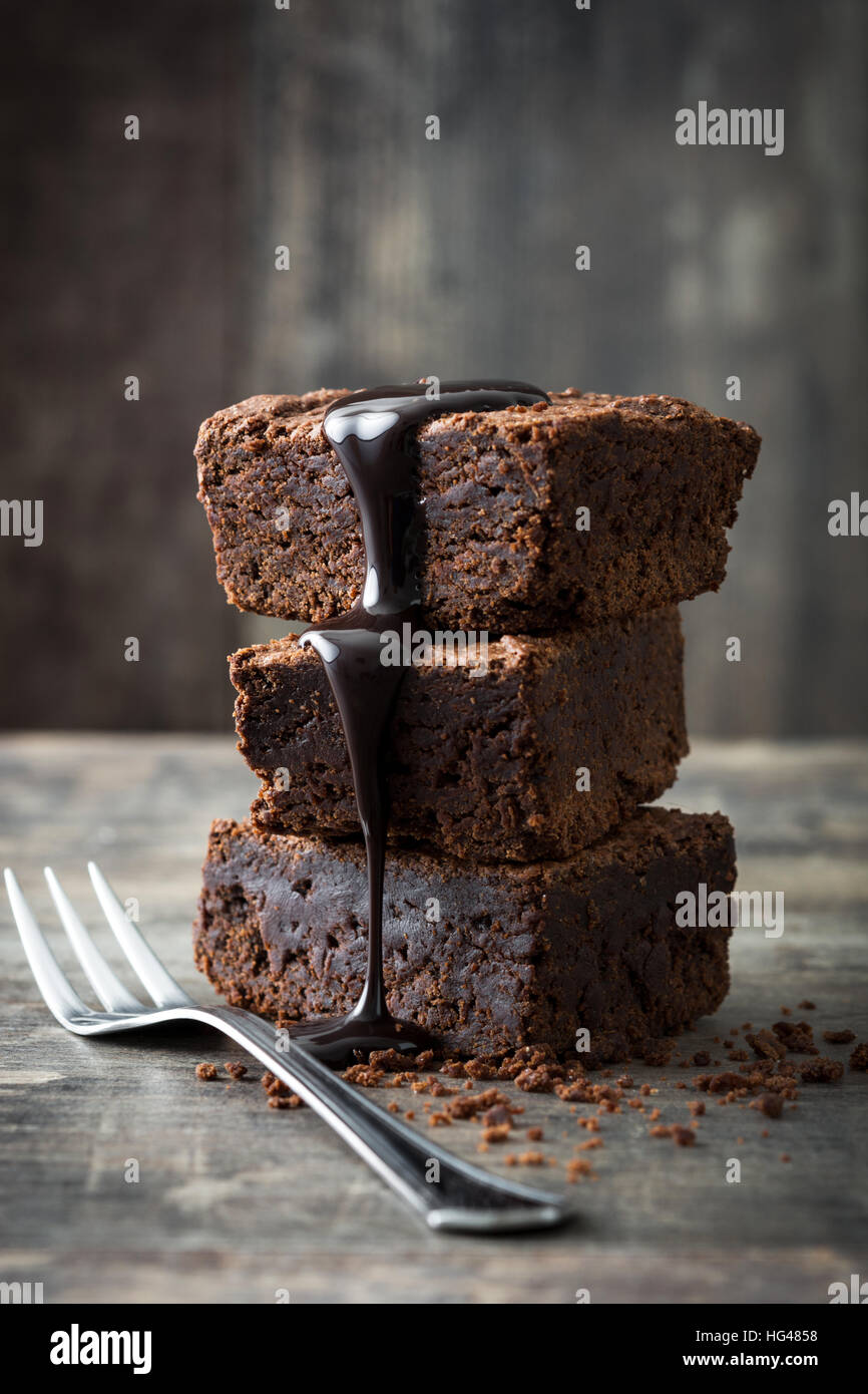 Schokoladenbrownie mit Schokoladensirup auf hölzernen Hintergrund Stockfoto