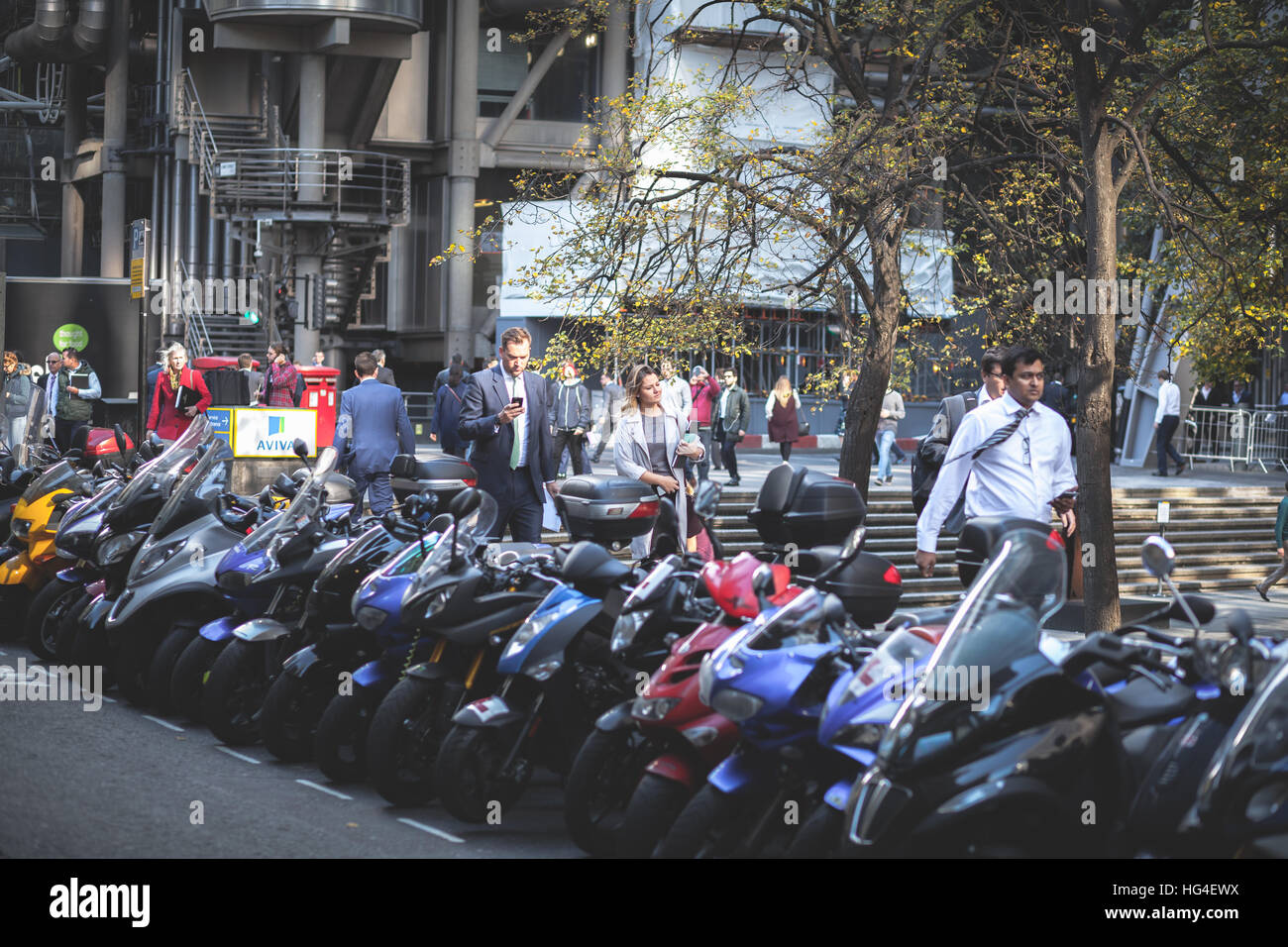 Menschen, die über dem Bürgersteig in der Nähe geparkten Roller in London UK Stockfoto