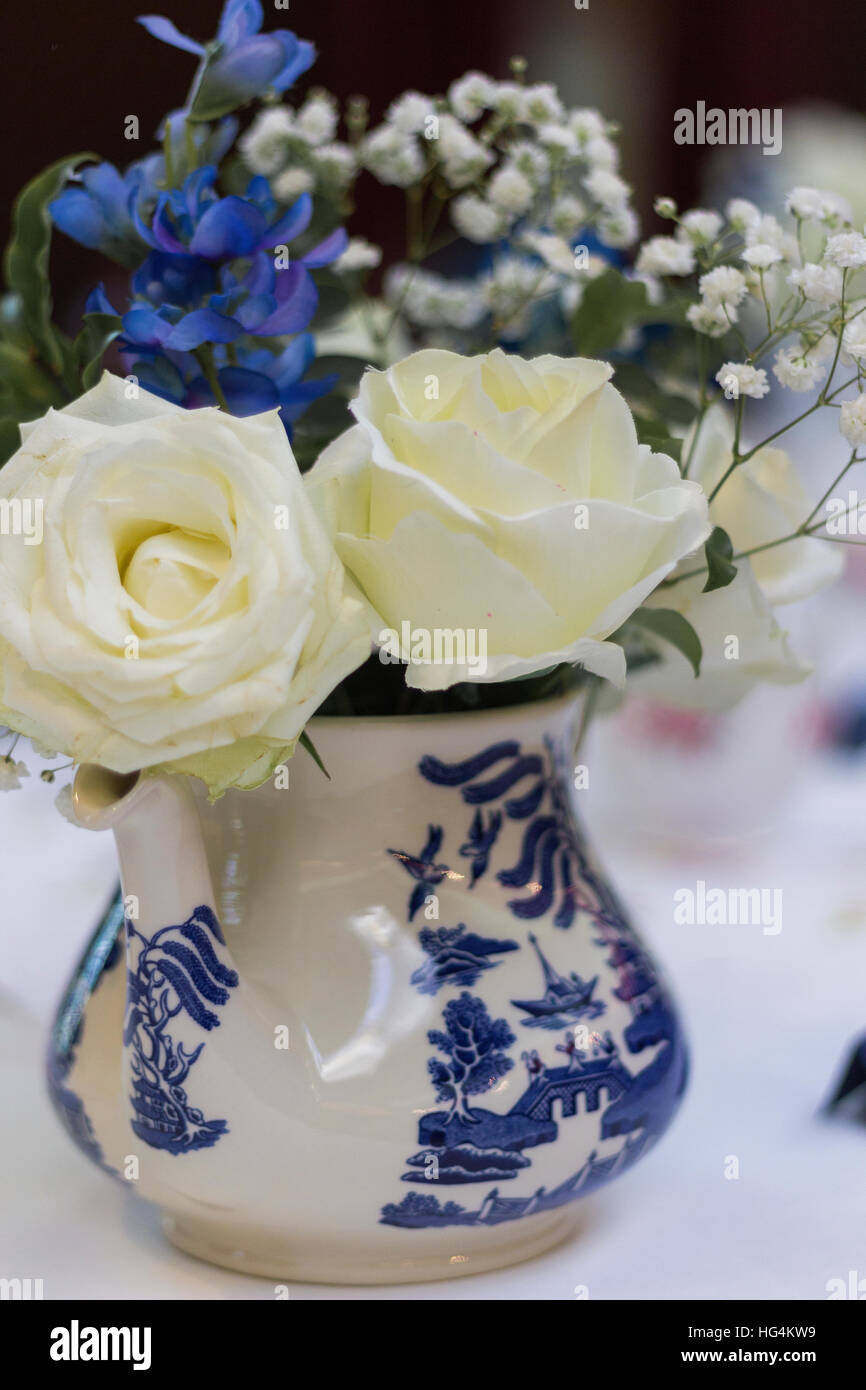 Weiße Rosen mit blauen Blüten und Baby Atem in blauen und weißen Transferware Muster Porzellan Krug, Hochzeit Herzstück Stockfoto