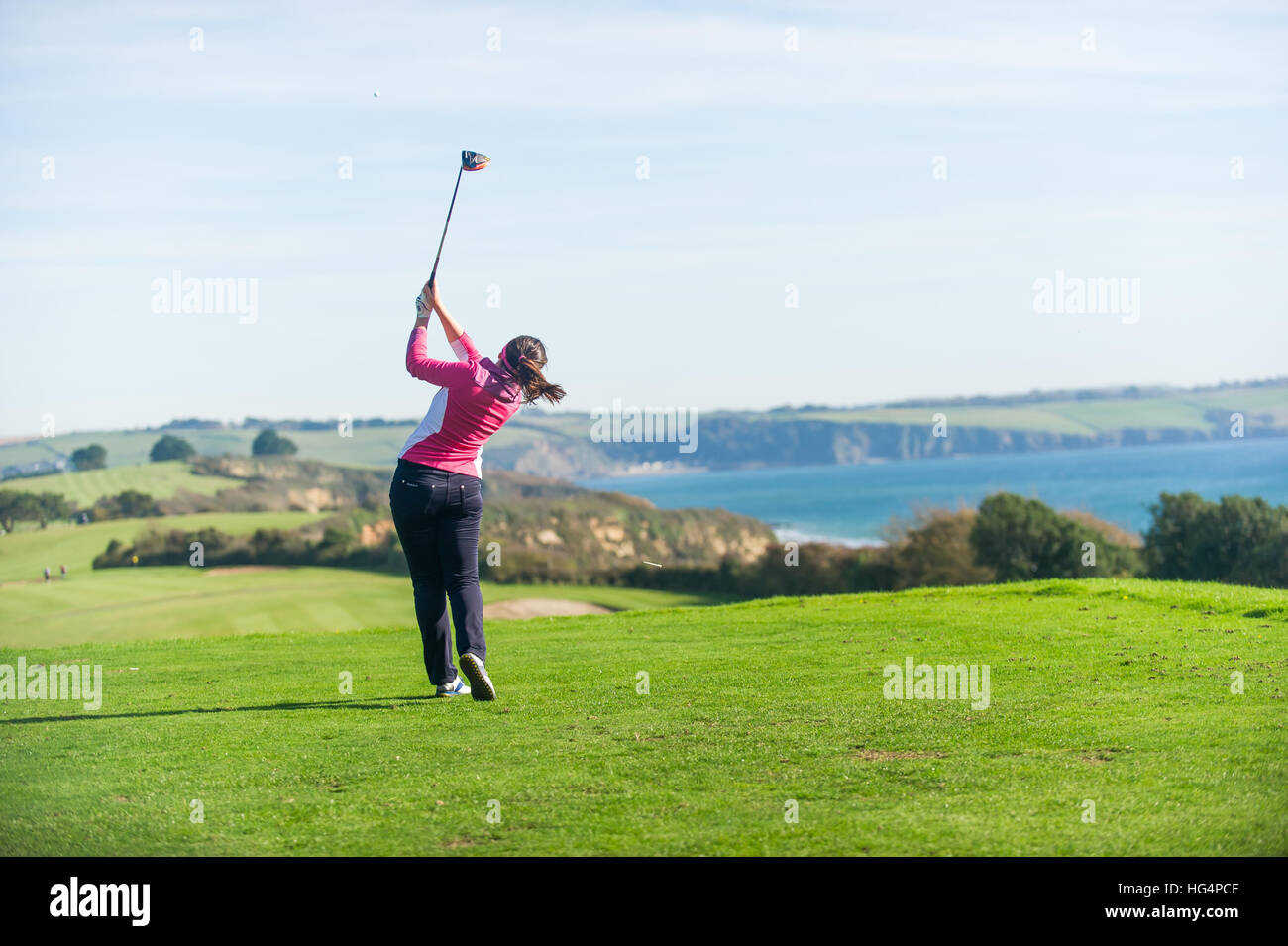 Ein junger weiblicher Golfer Abschlag am ersten Loch. Stockfoto
