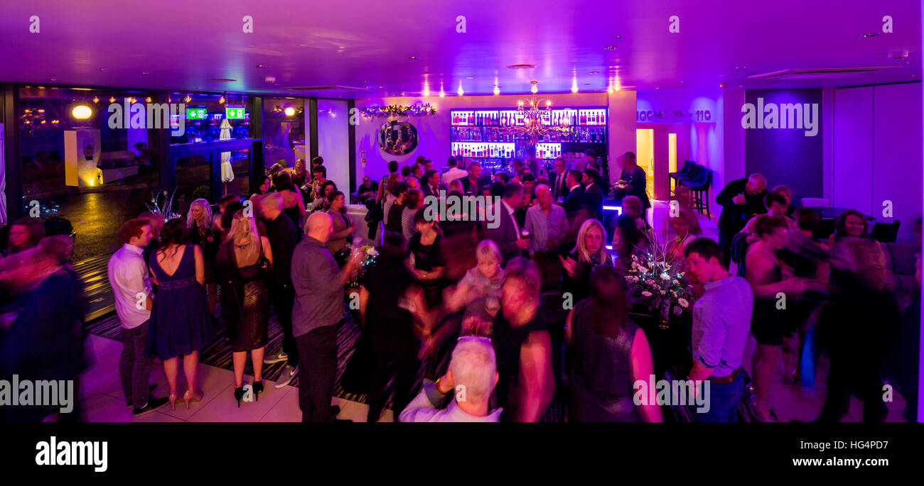 Eine Bar mit lila Beleuchtung mit Menschen gefüllt Stockfoto