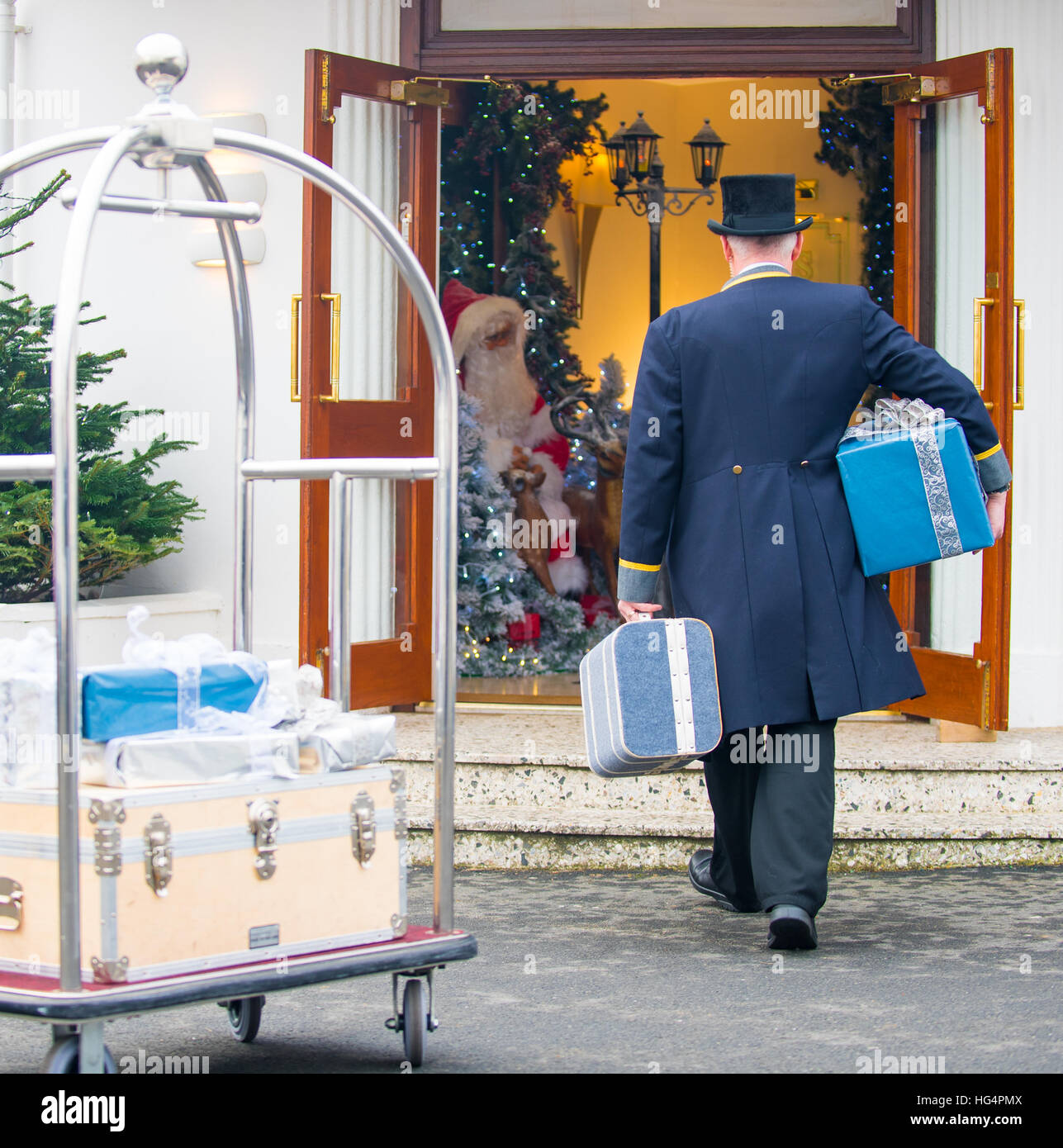 Ein Hotelportier Koffer in einer Lobby zu Weihnachten bringen Stockfoto
